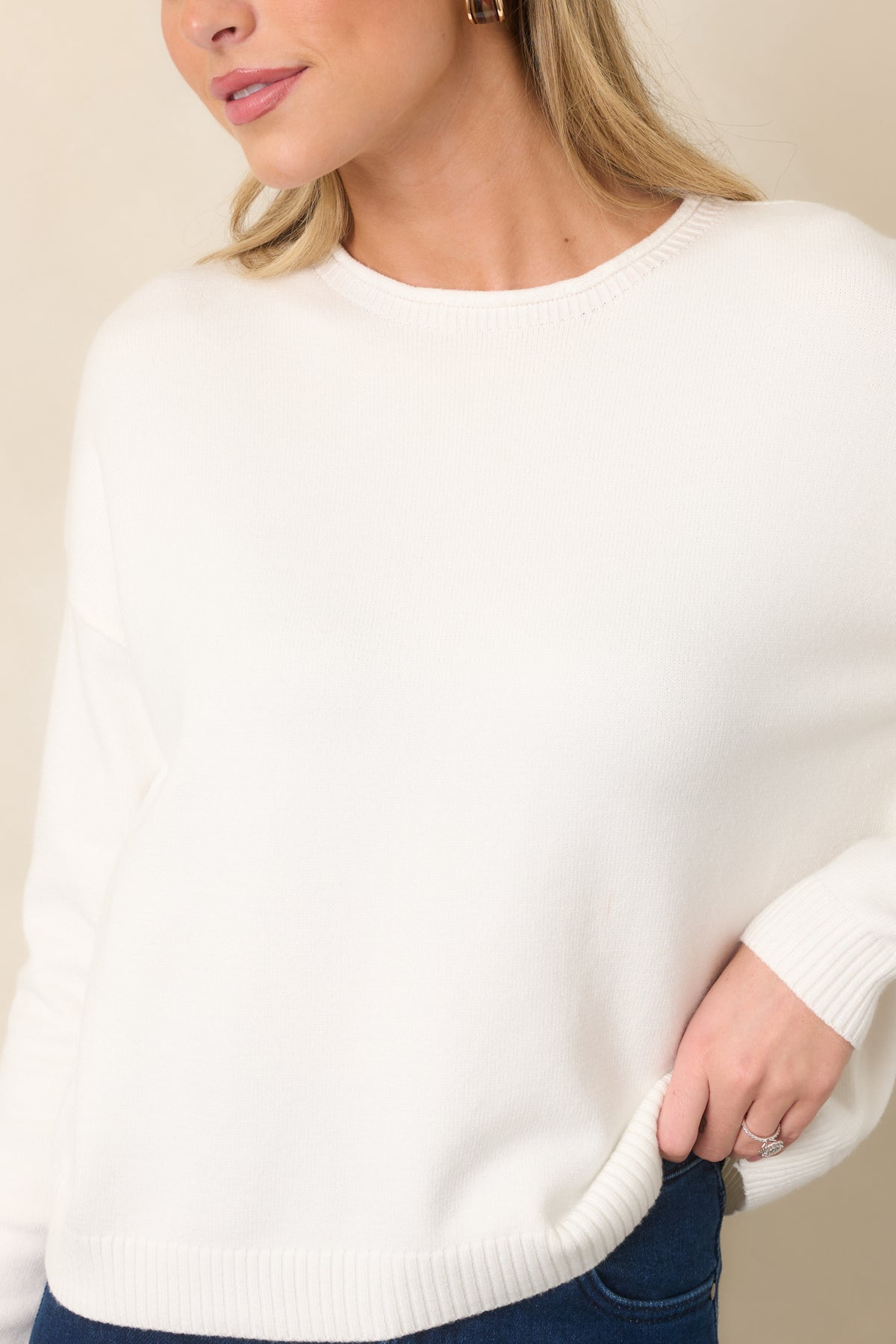 Close view of the fine knit texture and ribbed crew neckline on the ivory top.