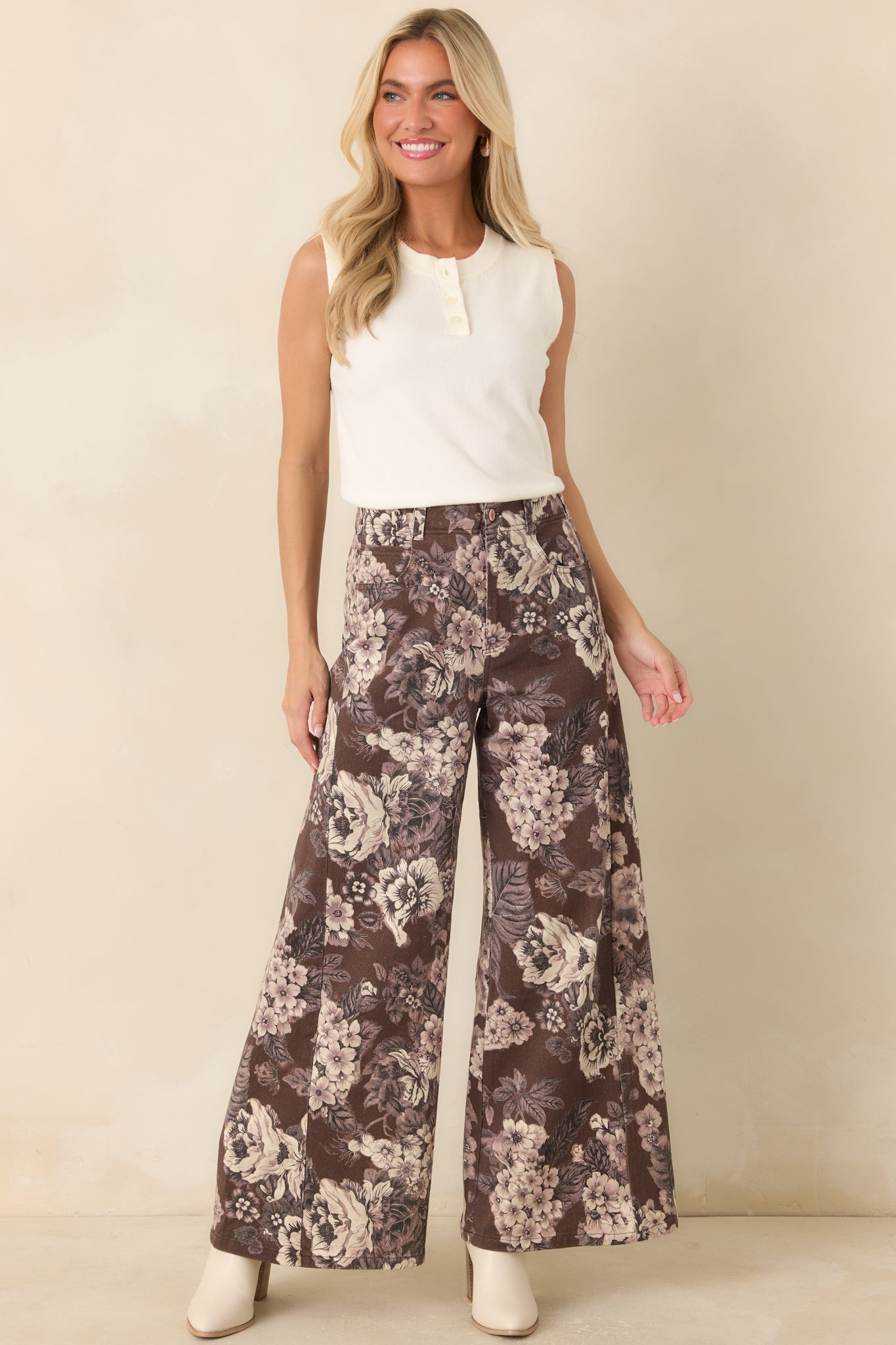 Statement wide-leg trousers designed with an ivory floral pattern, rich brown base, belt loops, and a polished button-and-zip front closure.