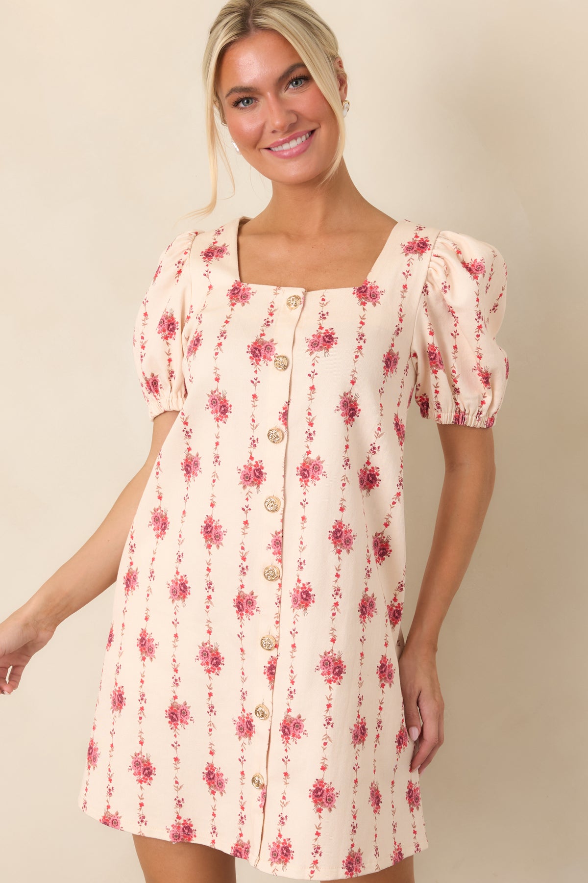 Decorative gold-tone buttons accent the front of this structured ivory floral mini dress with an elongated vine print.