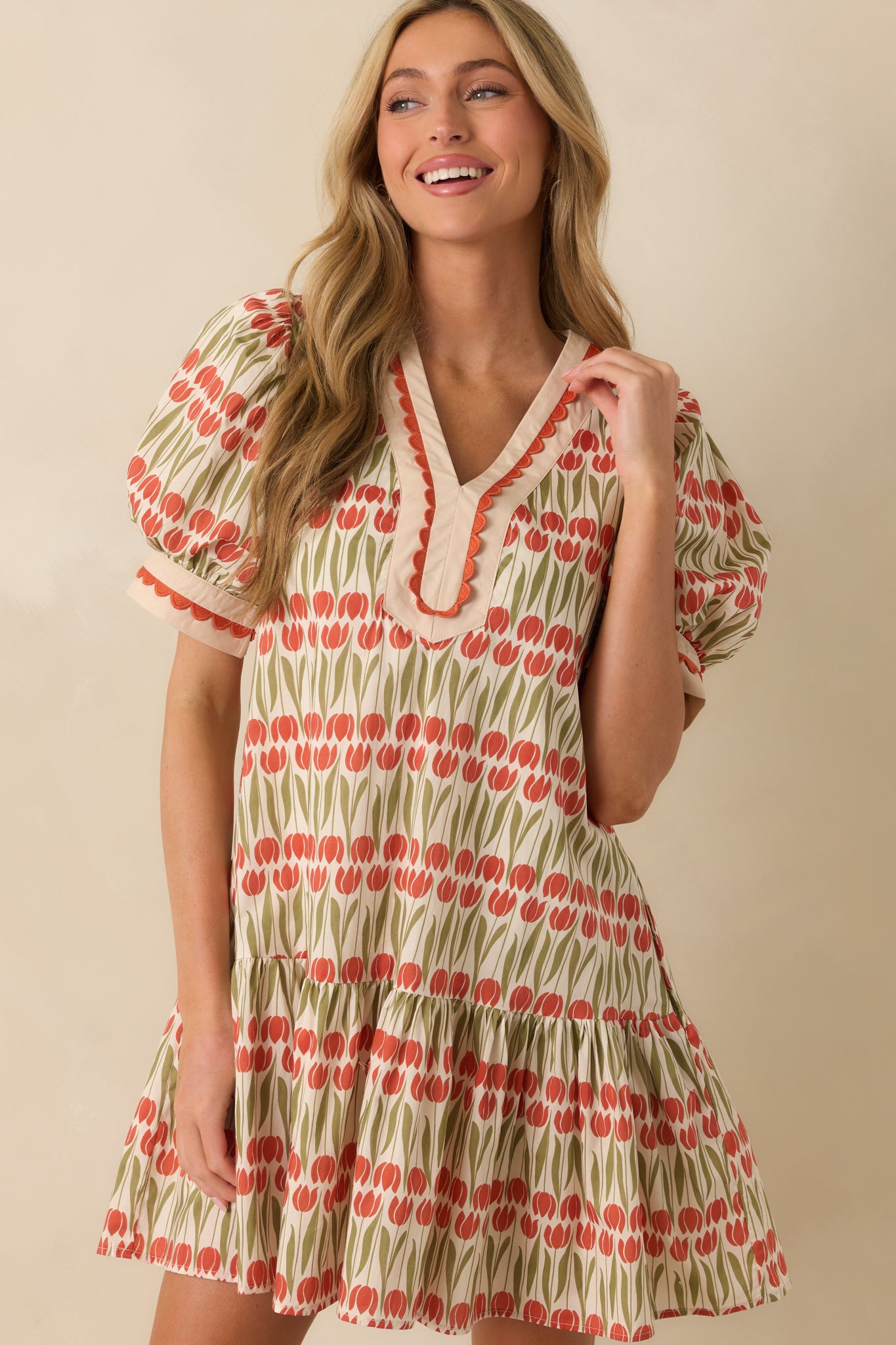 Close focus on the scalloped trim framing the v-neckline of the ivory floral dress.