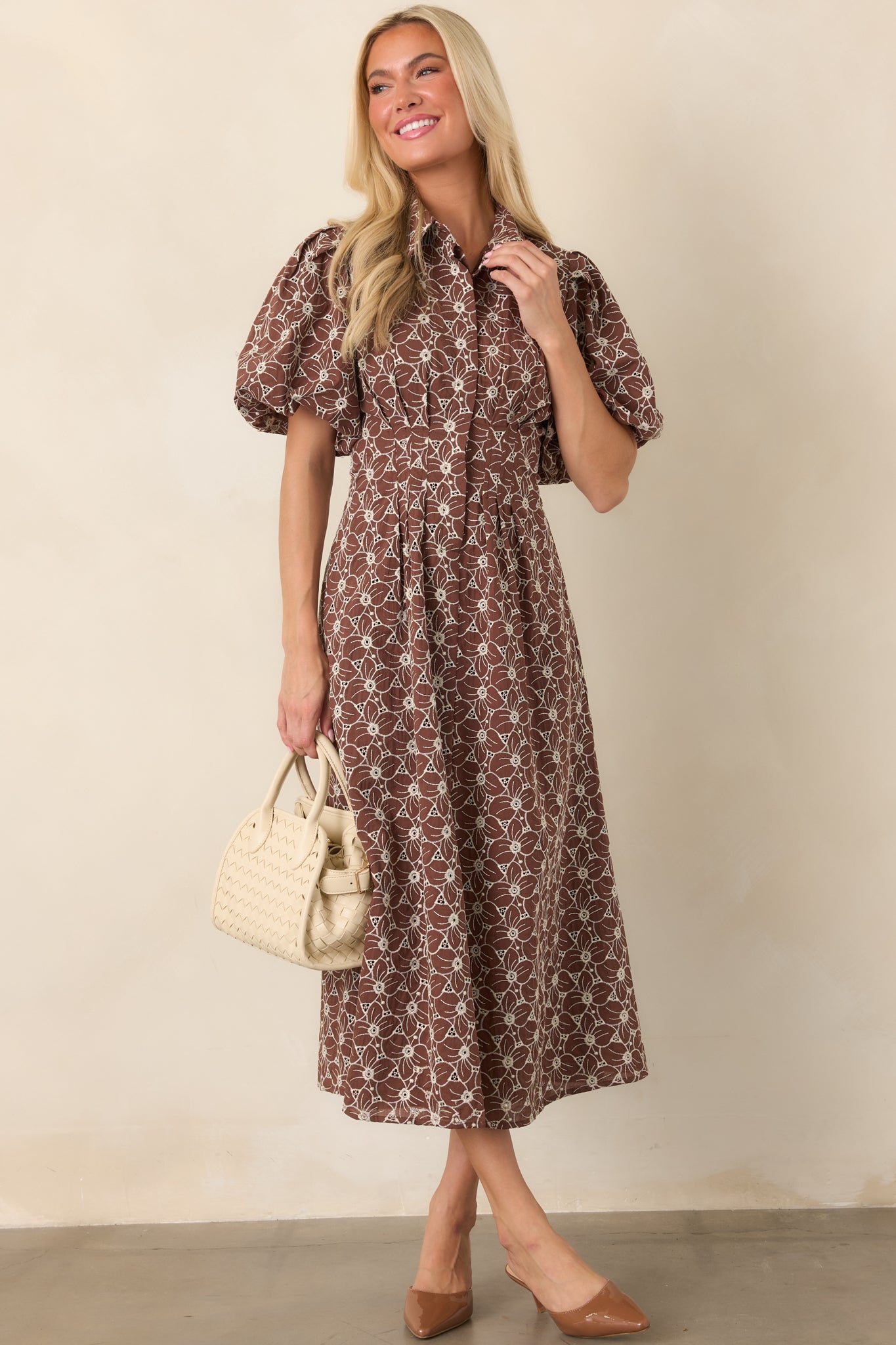 Full ivory cotton dress adorned with floral eyelet embroidery, finished with puff sleeves, a tailored waist, and a graceful full midi skirt.