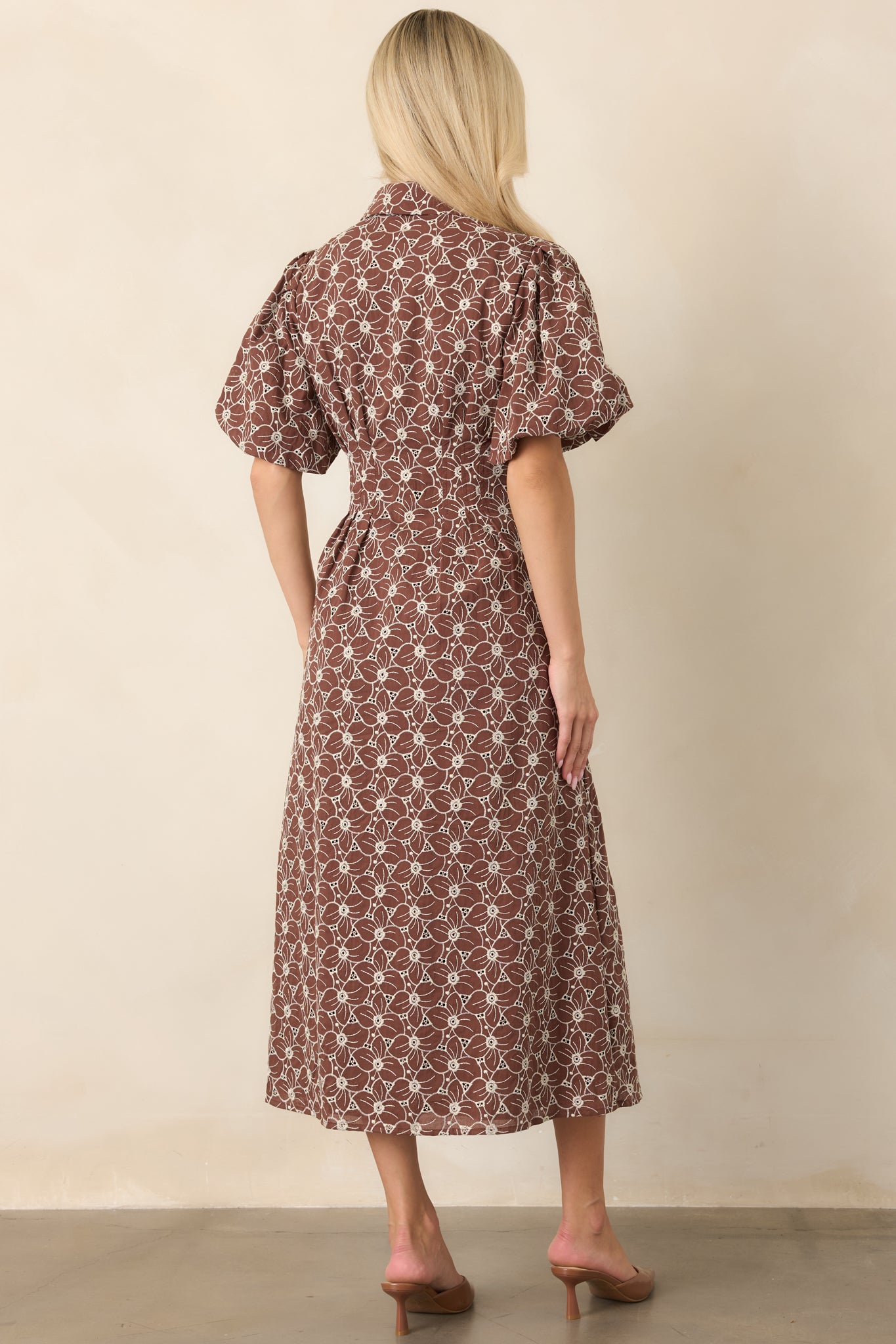 Rear view of the ivory floral eyelet midi dress, highlighting the fitted waist, short puff sleeves, full skirt, and embroidered cotton fabric.