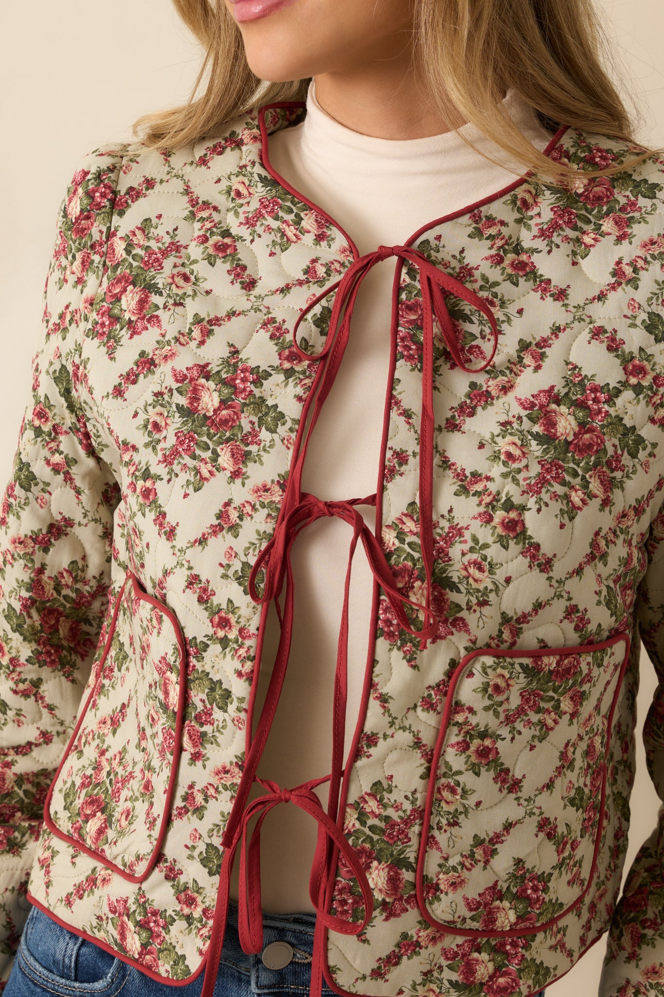 Detailed view of the floral quilted fabric with red binding and precise stitching for a cozy, crafted feel.