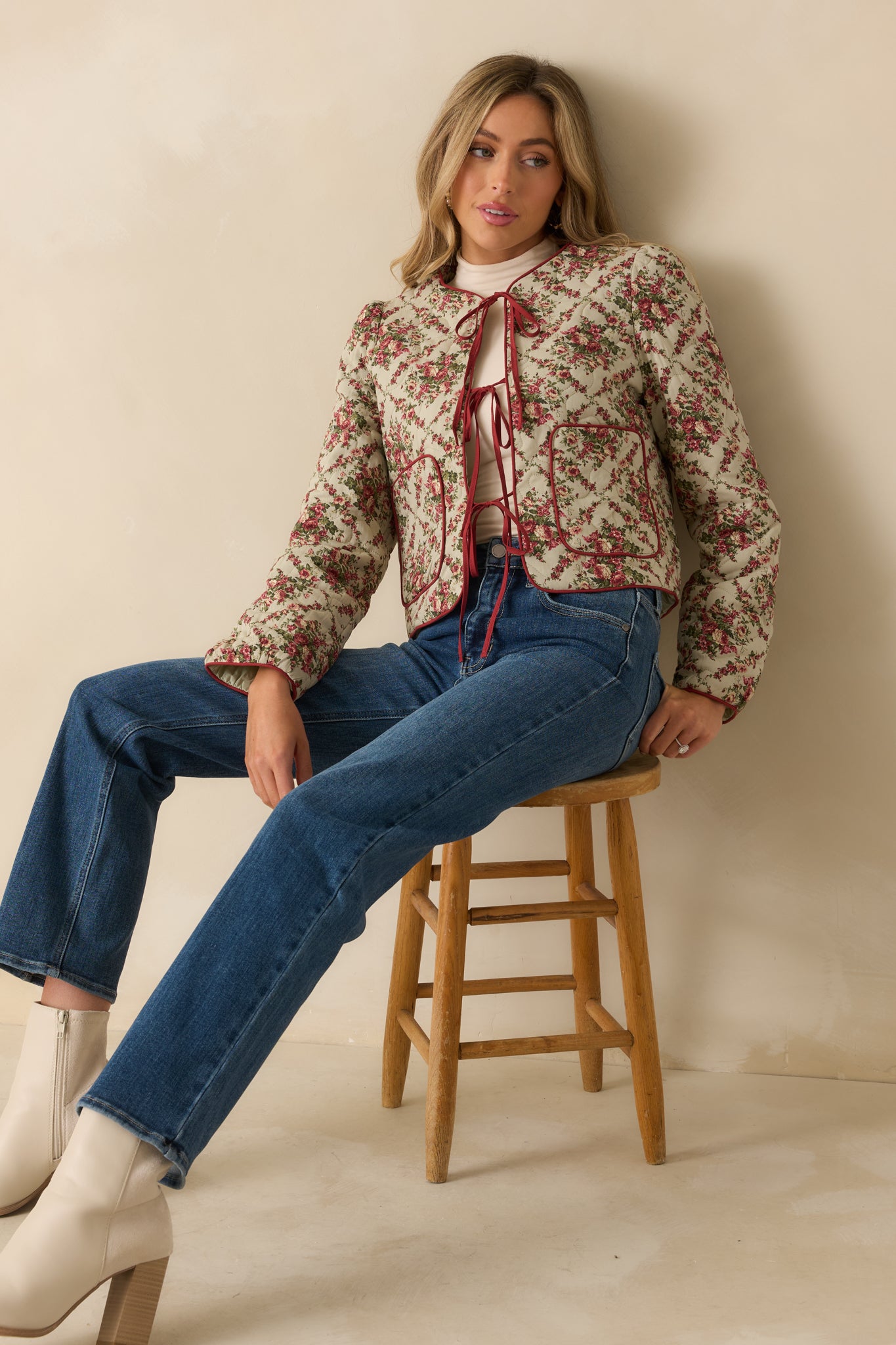 Ivory floral quilted jacket with red contrast edging, tie-front closure, and patch pockets, offering a cozy and polished layered look.