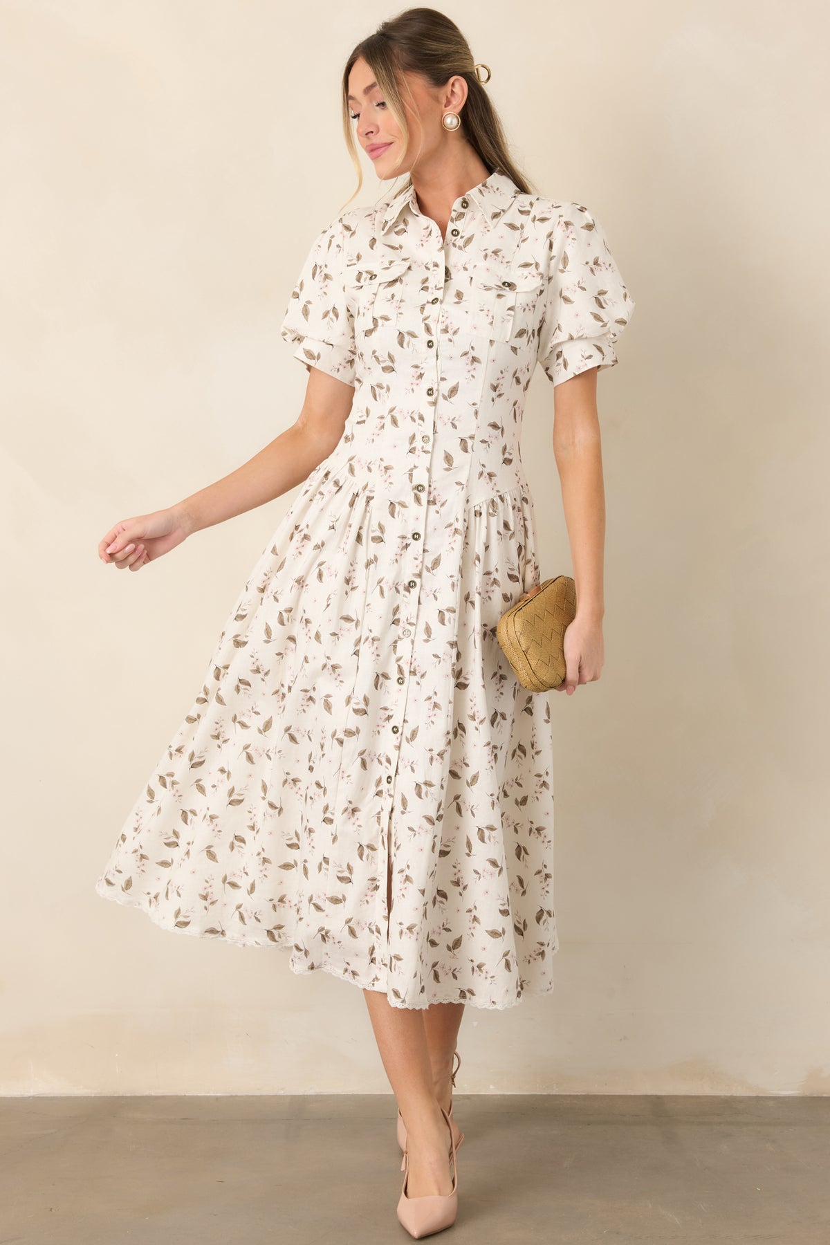 Ivory linen-blend midi dress features blush flowers, muted olive-taupe leaves, a pointed collar, button front, and short puff sleeves.