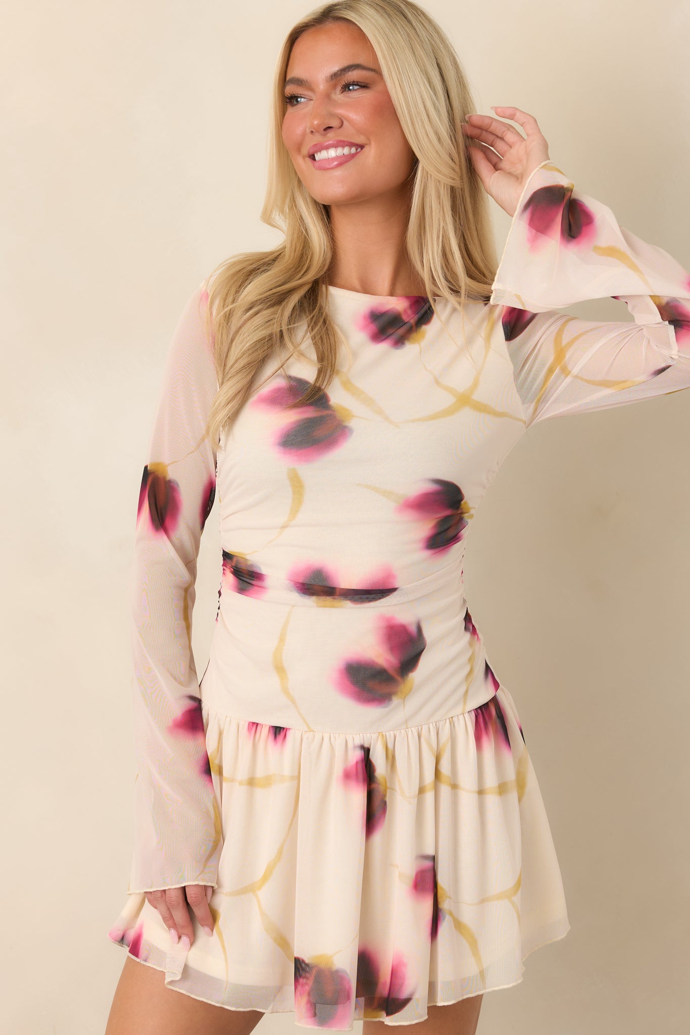 Close view of the ivory mesh dress showcasing its blurred floral pattern, wide boat neckline, and ruched fitted bodice.