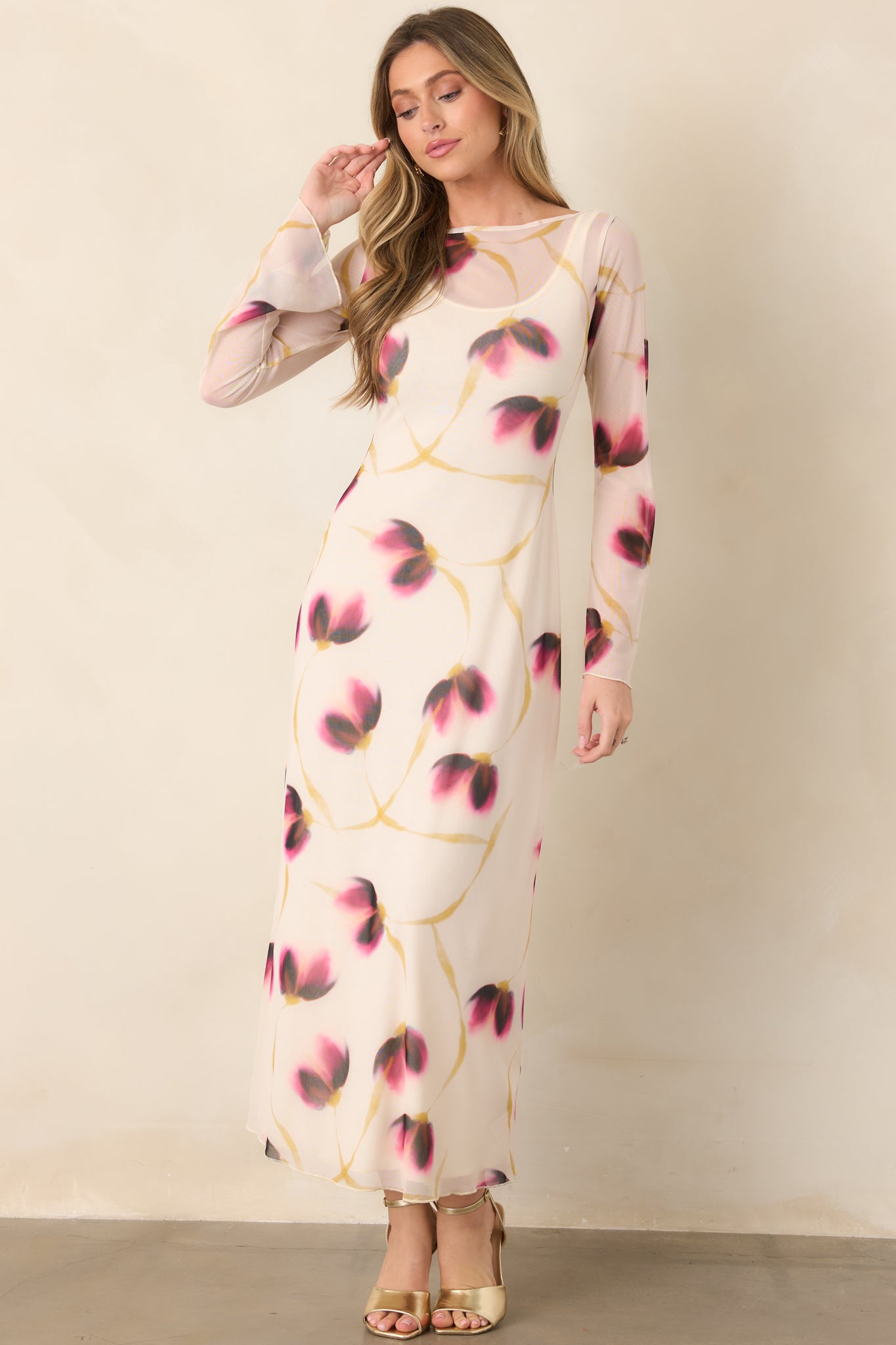 Ivory mesh maxi dress with blurred wine, pink, and golden floral accents, a wide boat neckline, long sleeves, and a close-fitting silhouette.