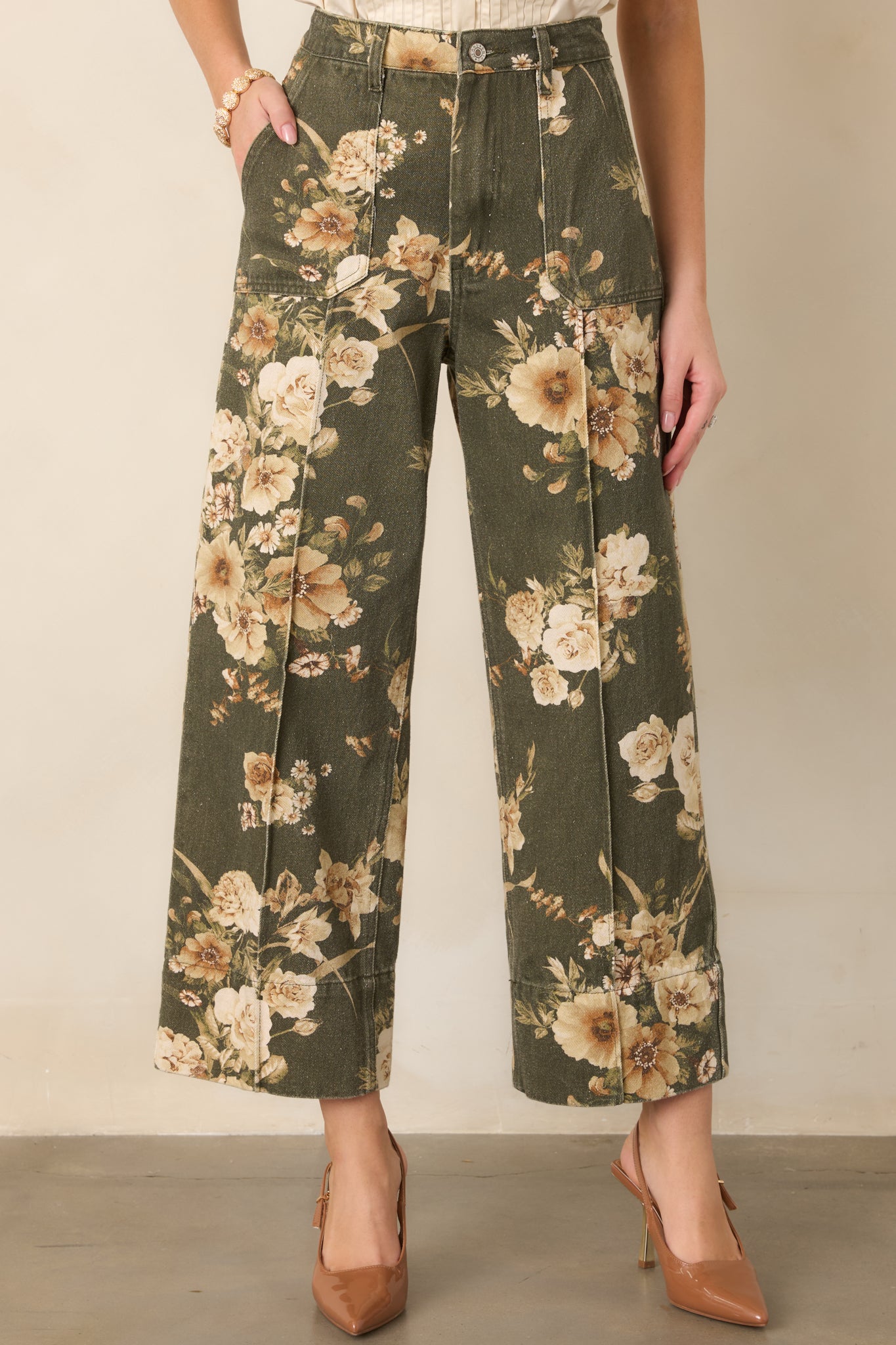 Ivory floral motifs stand out against the olive cotton fabric, complementing the pants' relaxed wide-leg silhouette.