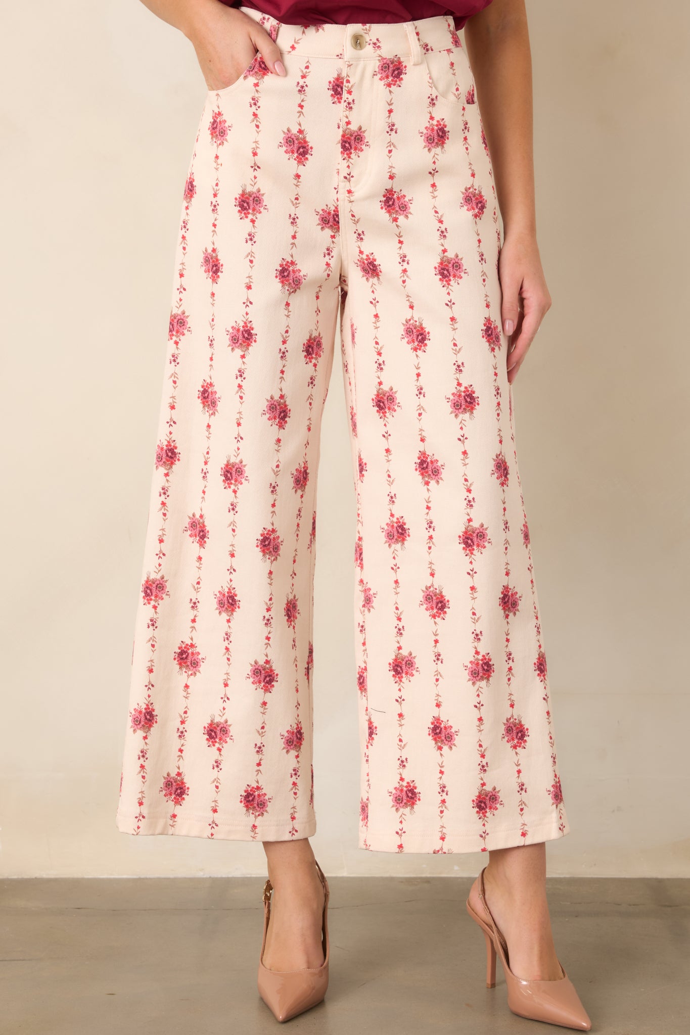 Close view of the ivory floral pants highlighting the high-rise waistband and rose bouquets arranged along trailing vines.