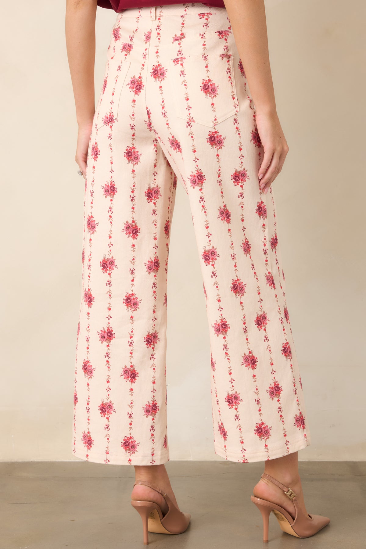 Rear view of the ivory floral pants showcasing trailing rose vines, high-rise waistband, belt loops, and functional back pockets.