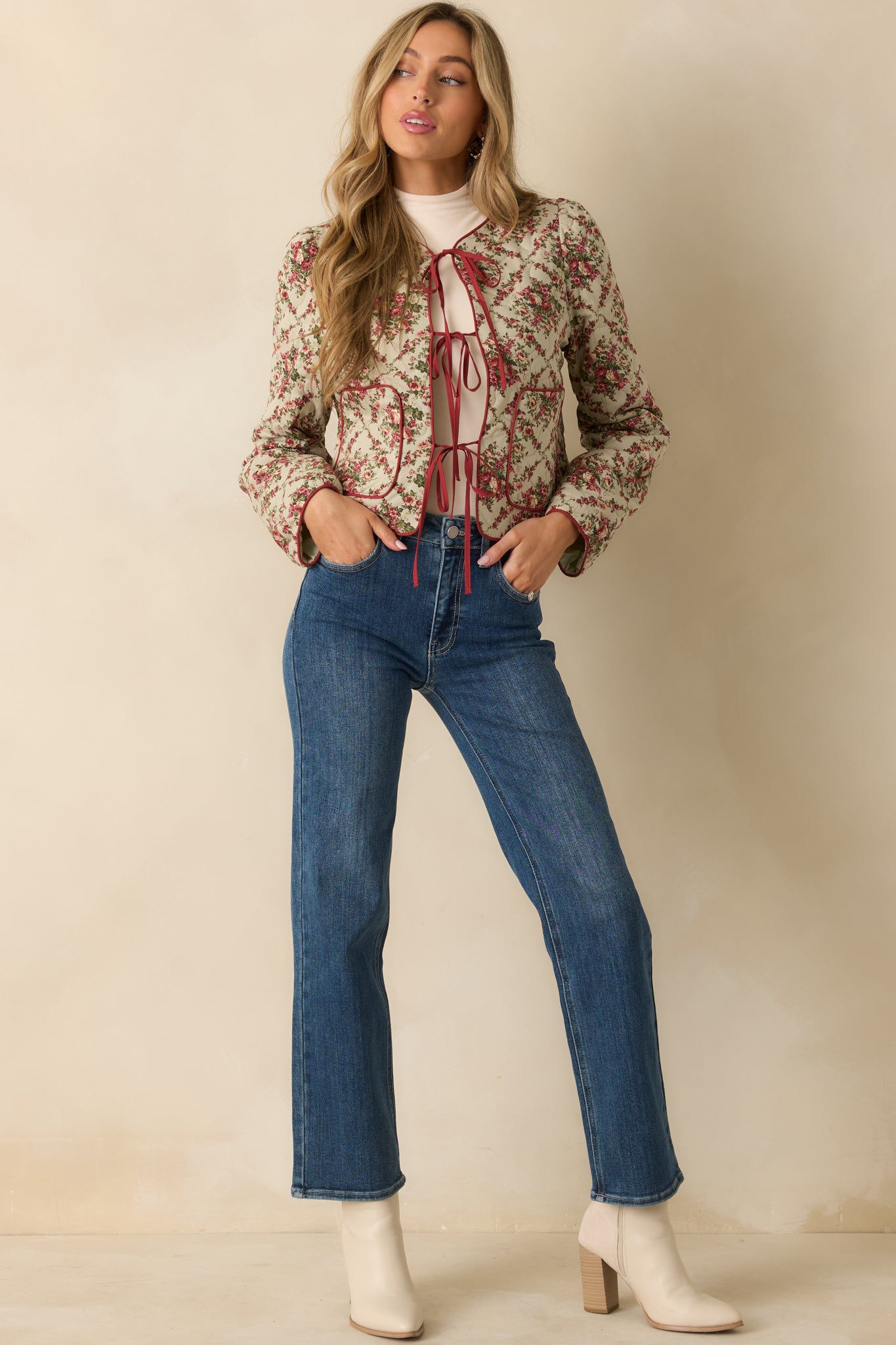 Ivory floral quilted jacket fully lined for warmth, designed with red trim and easy, open-front tie detail.