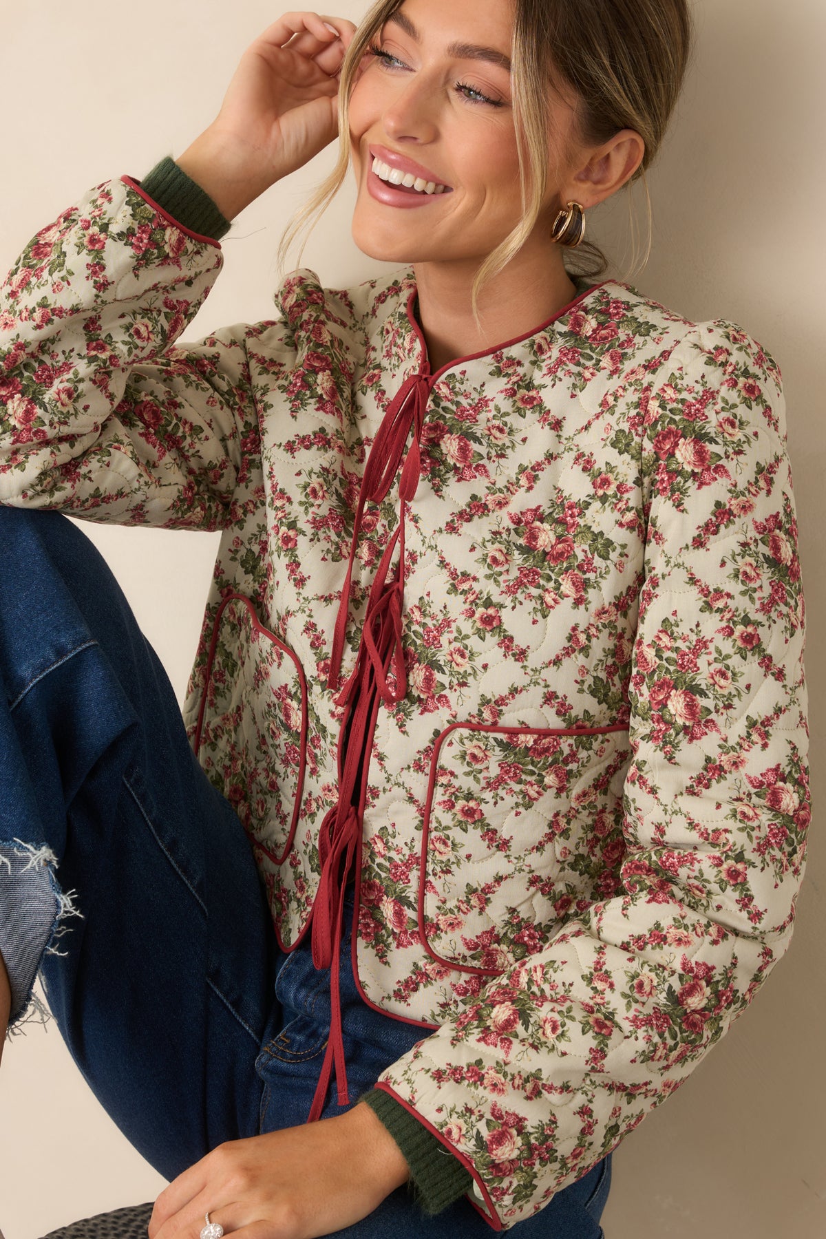 Floral ivory quilted jacket featuring red contrast binding, functional patch pockets, and soft lightly padded fabric.