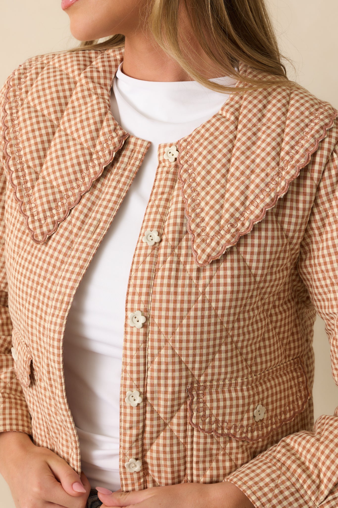 Ivory flower button and quilted diamond stitching detail on the light rust gingham jacket.