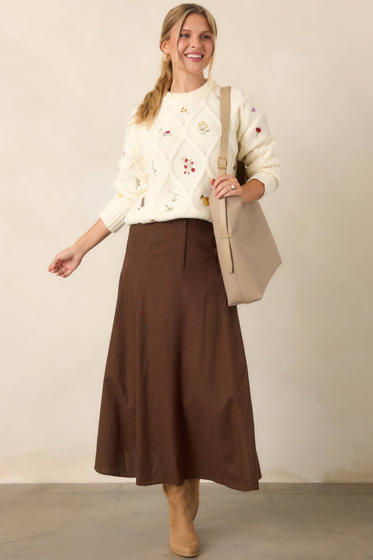 Garden-inspired ivory knit top with colorful embroidered motifs, relaxed long sleeves, classic crew neckline, and structured ribbed trim.