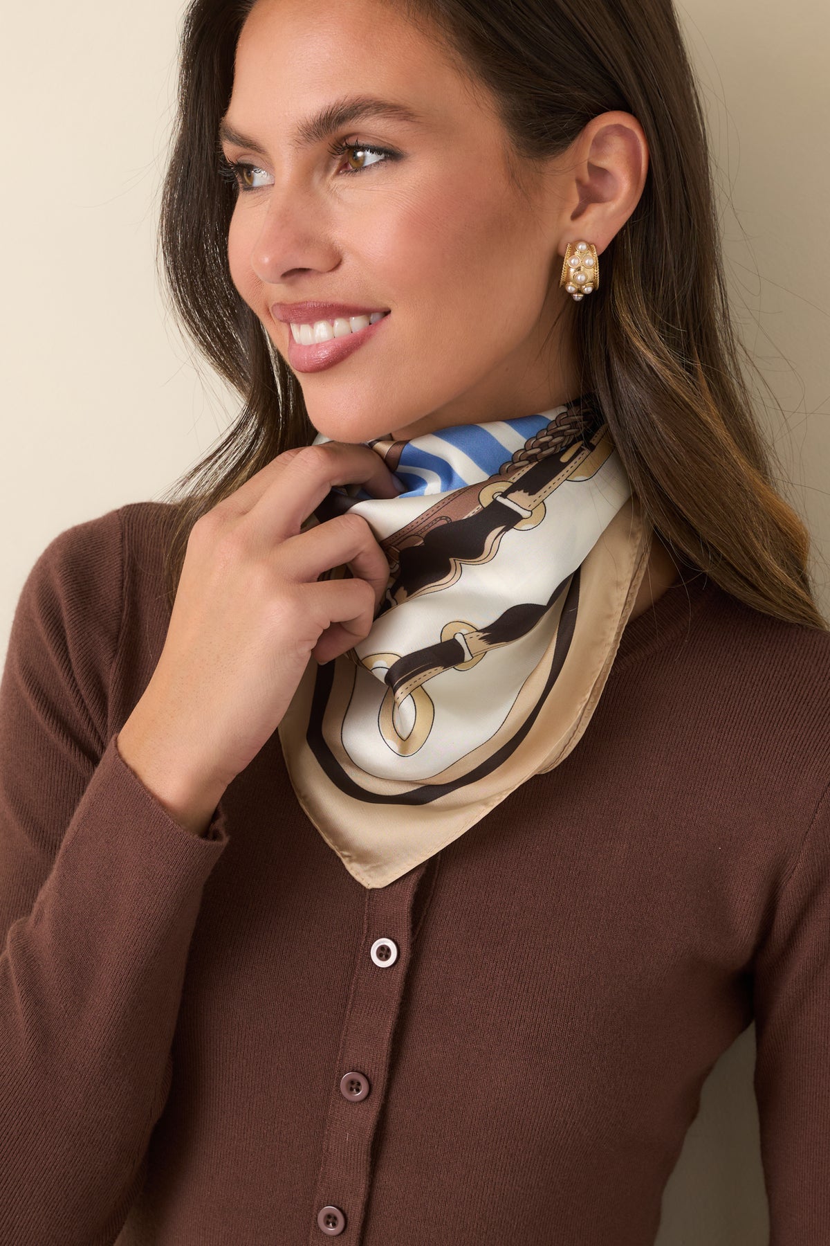 Ivory scarf displaying gold-tone buckles, braided straps, and light blue stripe accents.