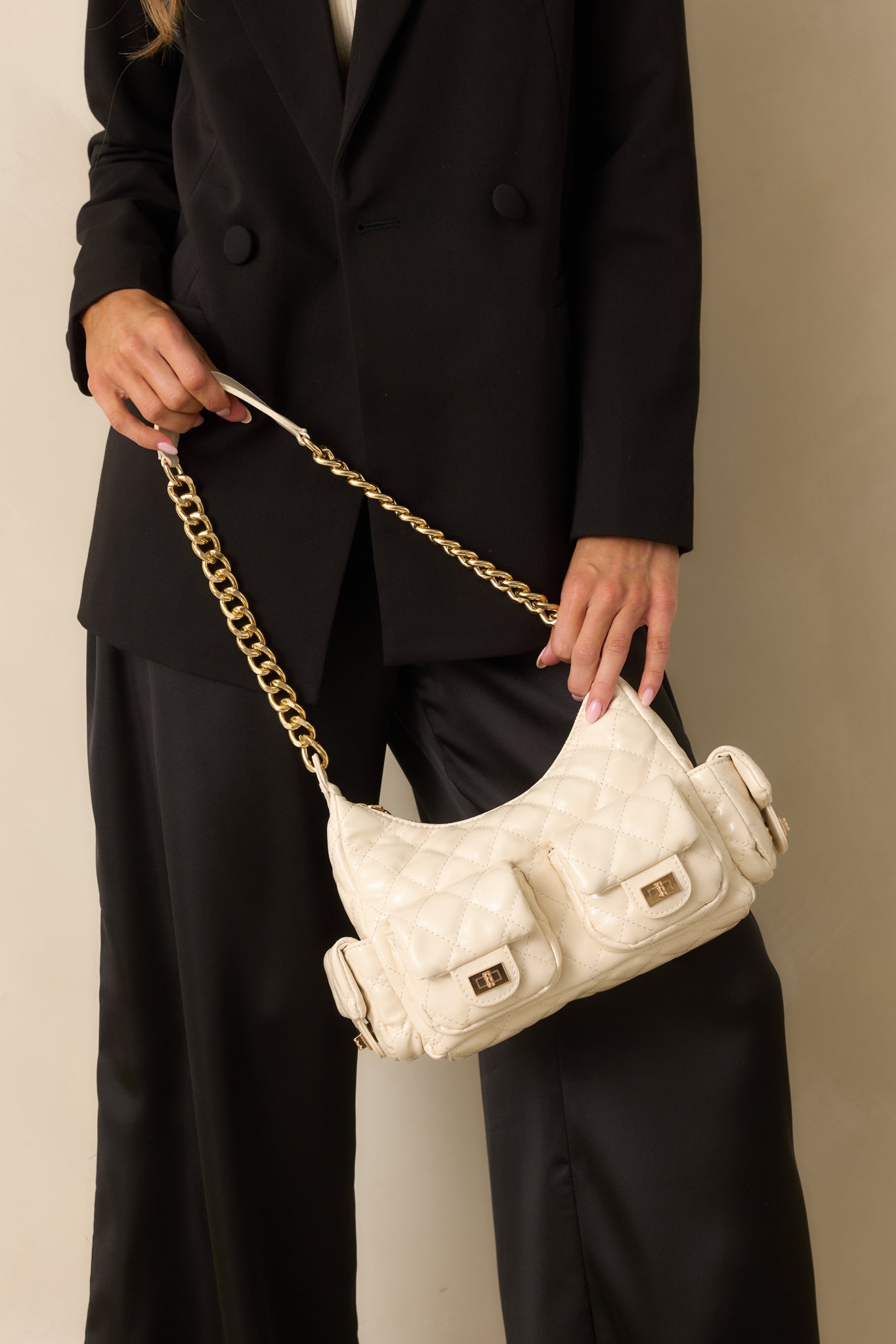 Front view of the ivory quilted handbag showing gold chain shoulder strap and multiple flap pockets.