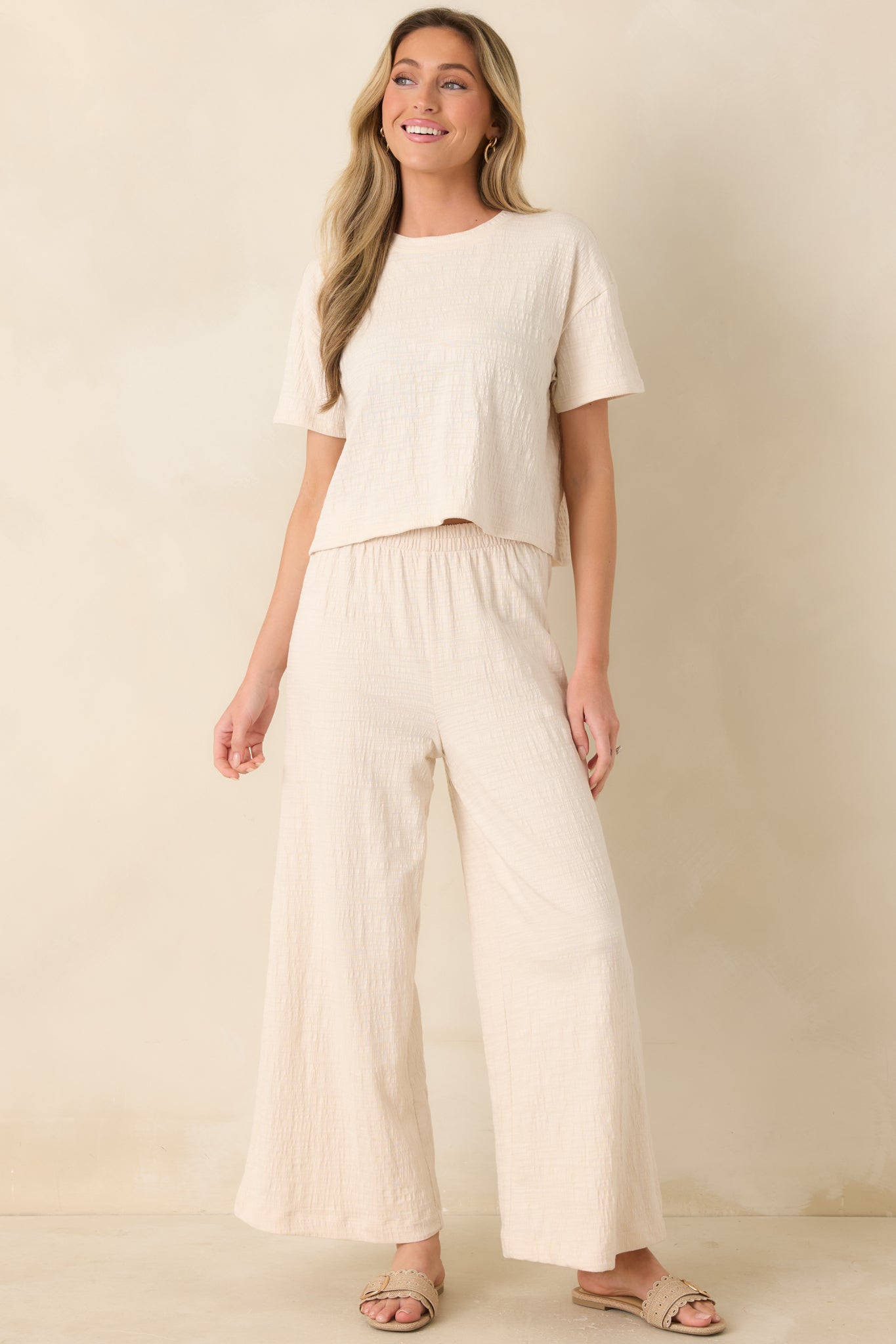 Ivory high-rise pants with elastic waistband and wide-leg cropped silhouette.