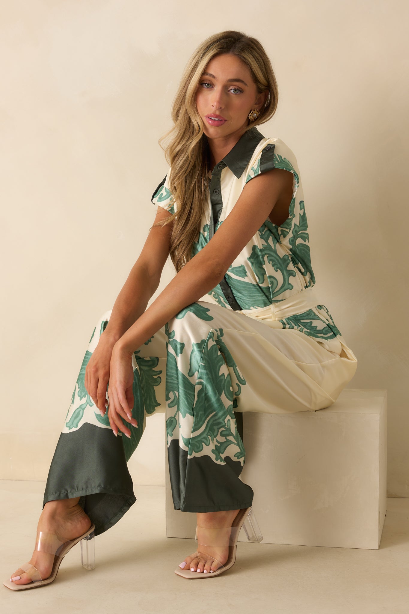 Ivory jumpsuit with green baroque-inspired border print, collared neckline, cuffed short sleeves, and wide-leg silhouette.