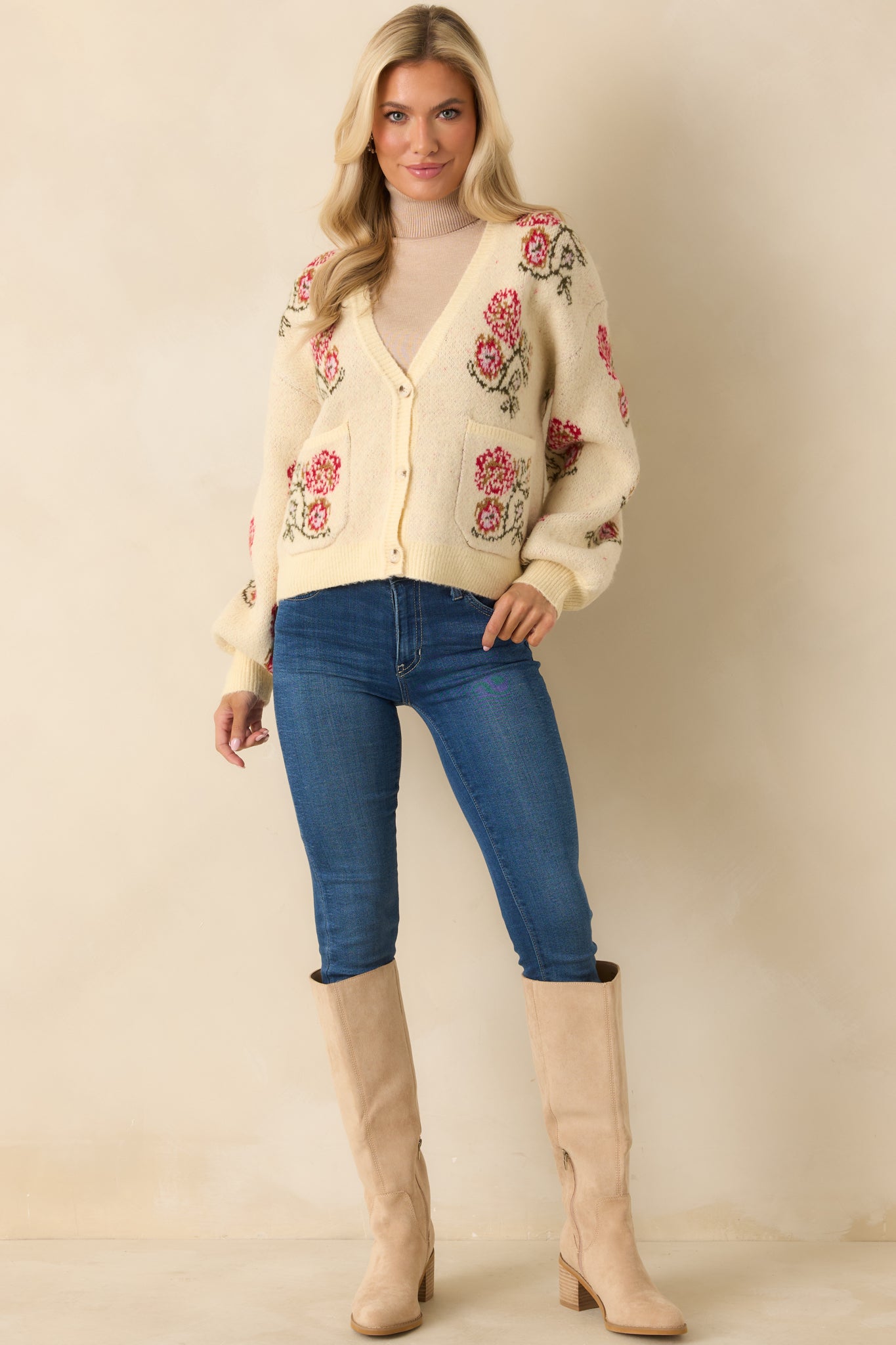 Ivory knit cardigan with a relaxed silhouette, V-neckline, and vintage-style floral motifs on the front pockets.