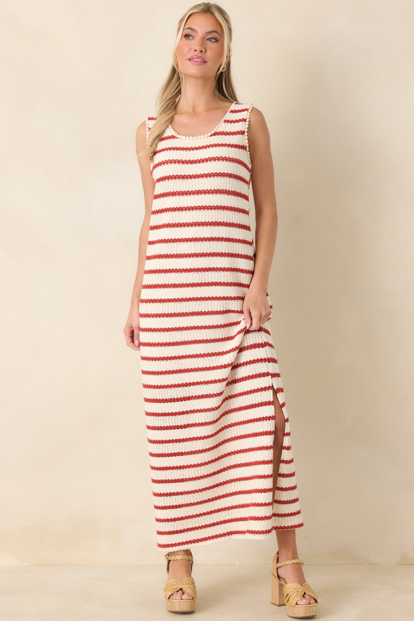 Soft ivory knit dress patterned with red stripes, designed with a sleeveless silhouette and side slit for movement.