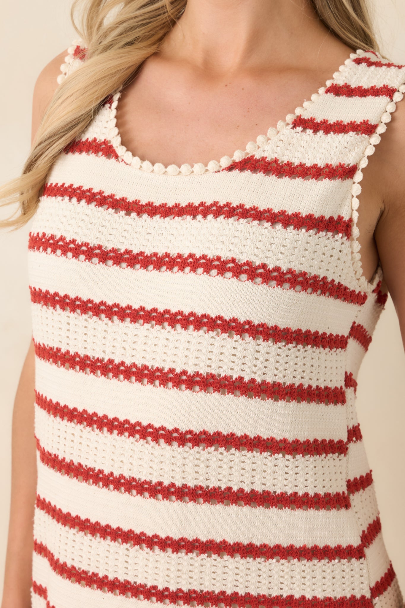 Close view of the ivory knit fabric featuring classic red stripes and a smooth sleeveless neckline.