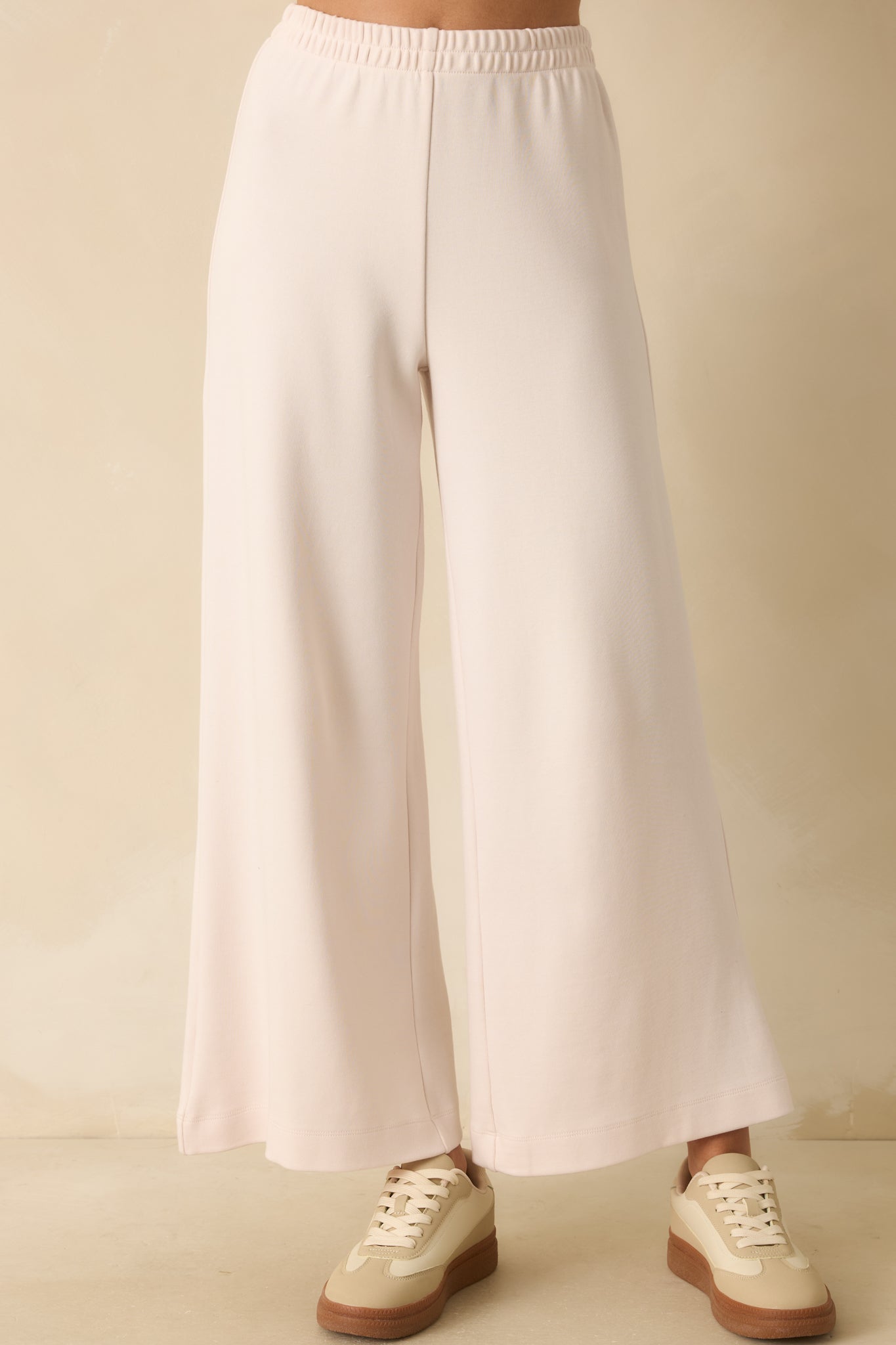 Close crop showing elastic waistband and knit texture on ivory wide-leg pants.
