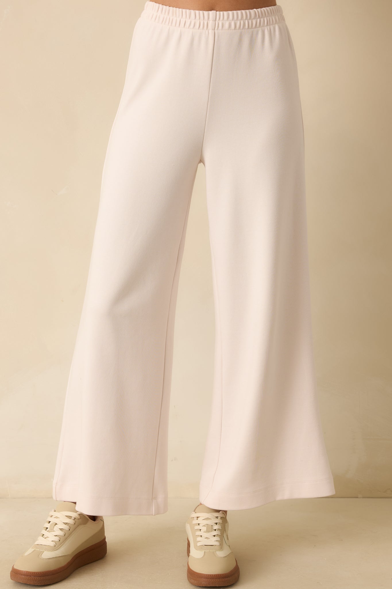 Detail of fabric drape and relaxed fit of ivory knit pants.