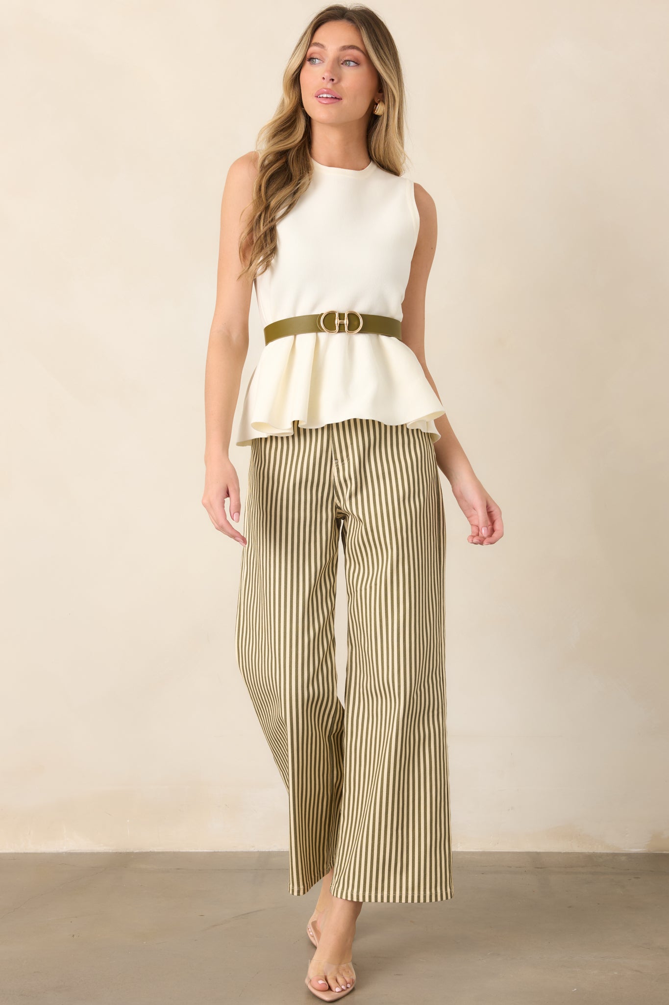 Ivory knit peplum top showcasing a streamlined sleeveless silhouette, smooth fabric, rounded neckline, and gently curved hem that flares from the waist.