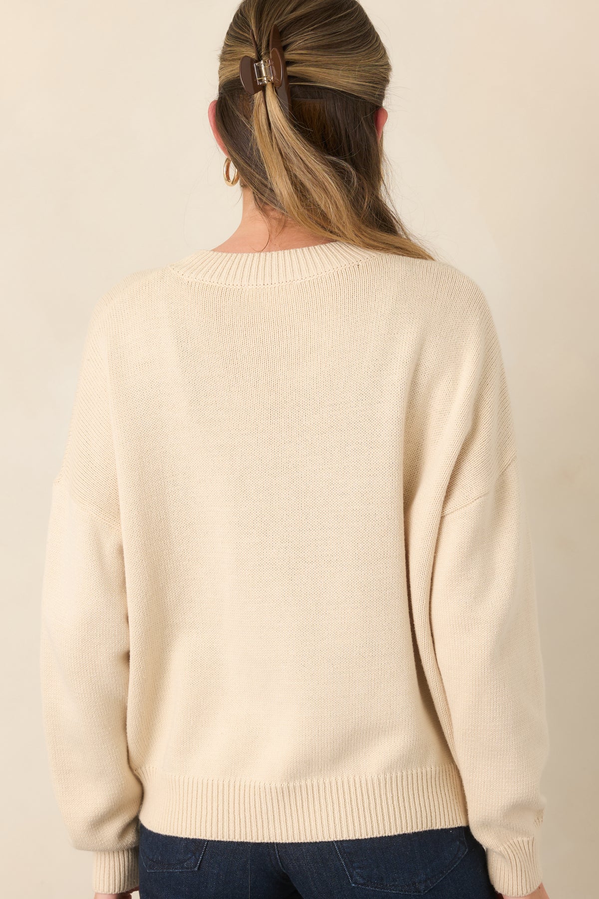 Rear view of the ivory knit pullover showcasing the relaxed fit, long drop-shoulder sleeves, and ribbed hem.
