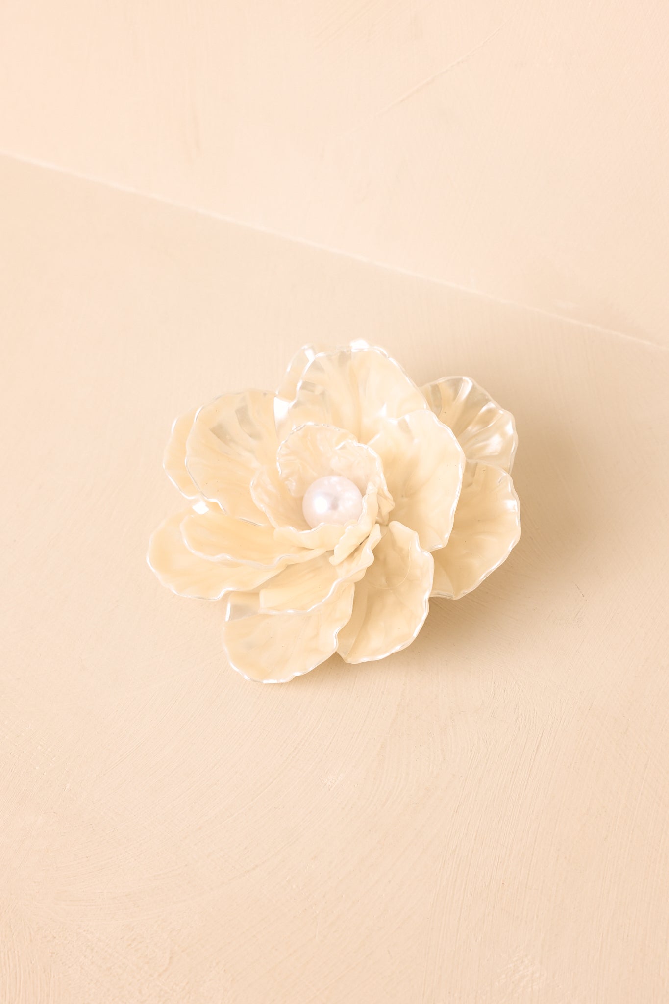 Layered ivory floral piece showcasing luminous petals, pearl center detail, and elegant versatile design.
