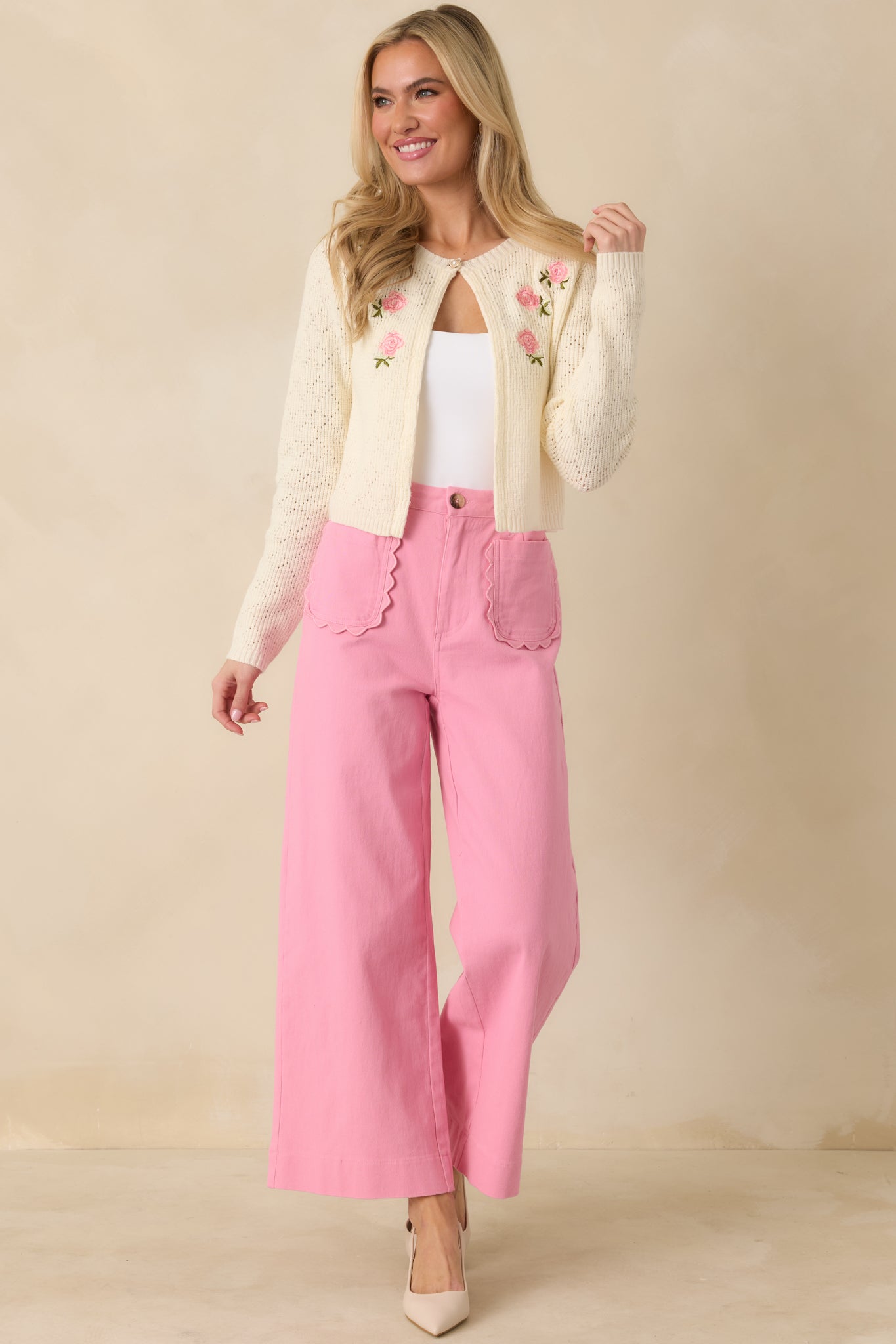 Ivory lightweight cardigan adorned in delicate pink floral embroidery, featuring a single pearl-look button at the neckline and a romantic heirloom feel.