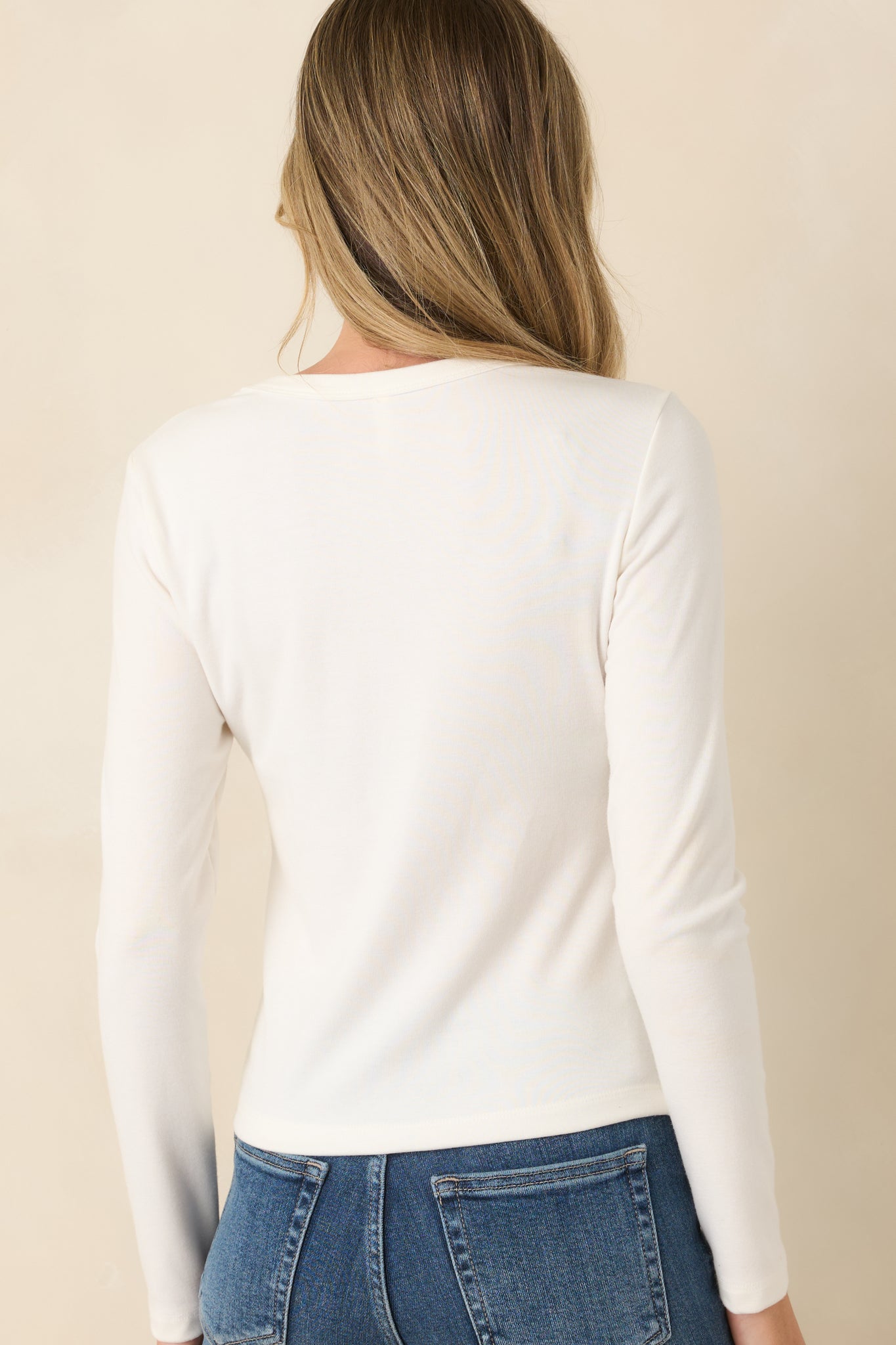 Back view of the ivory long sleeve top showcasing the fitted silhouette and smooth fabric finish.