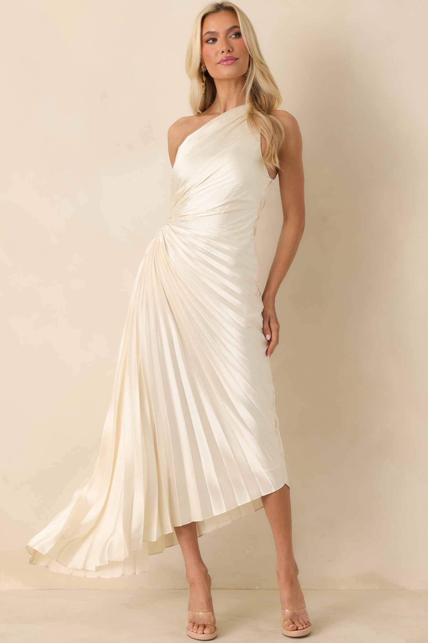 Light ivory maxi dress with an asymmetric one-shoulder neckline, pleated bodice, and flowing pleated skirt.