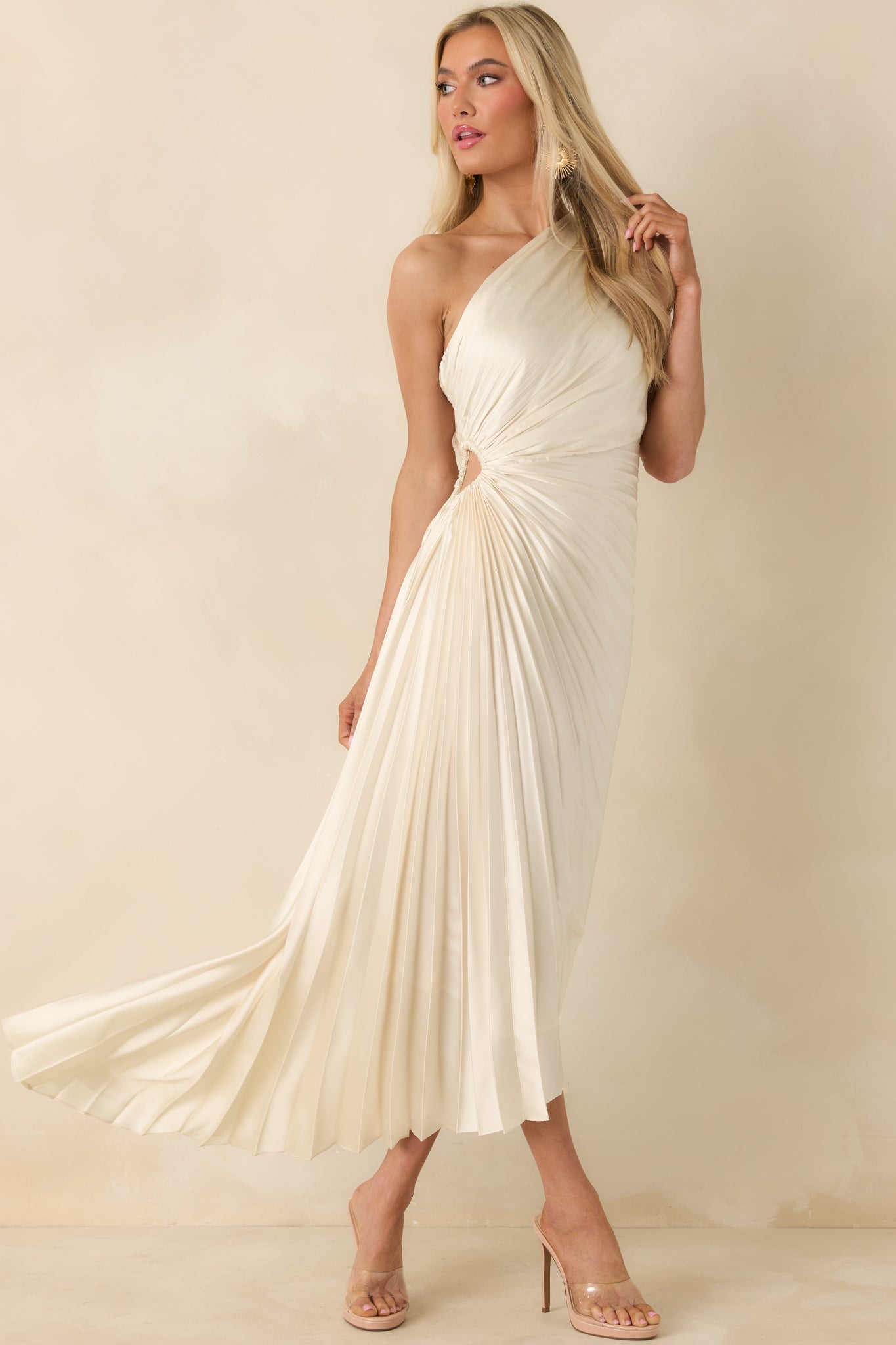 Light ivory maxi dress with an asymmetric one-shoulder neckline, fitted pleated bodice, side cutout, and flowing pleated skirt.