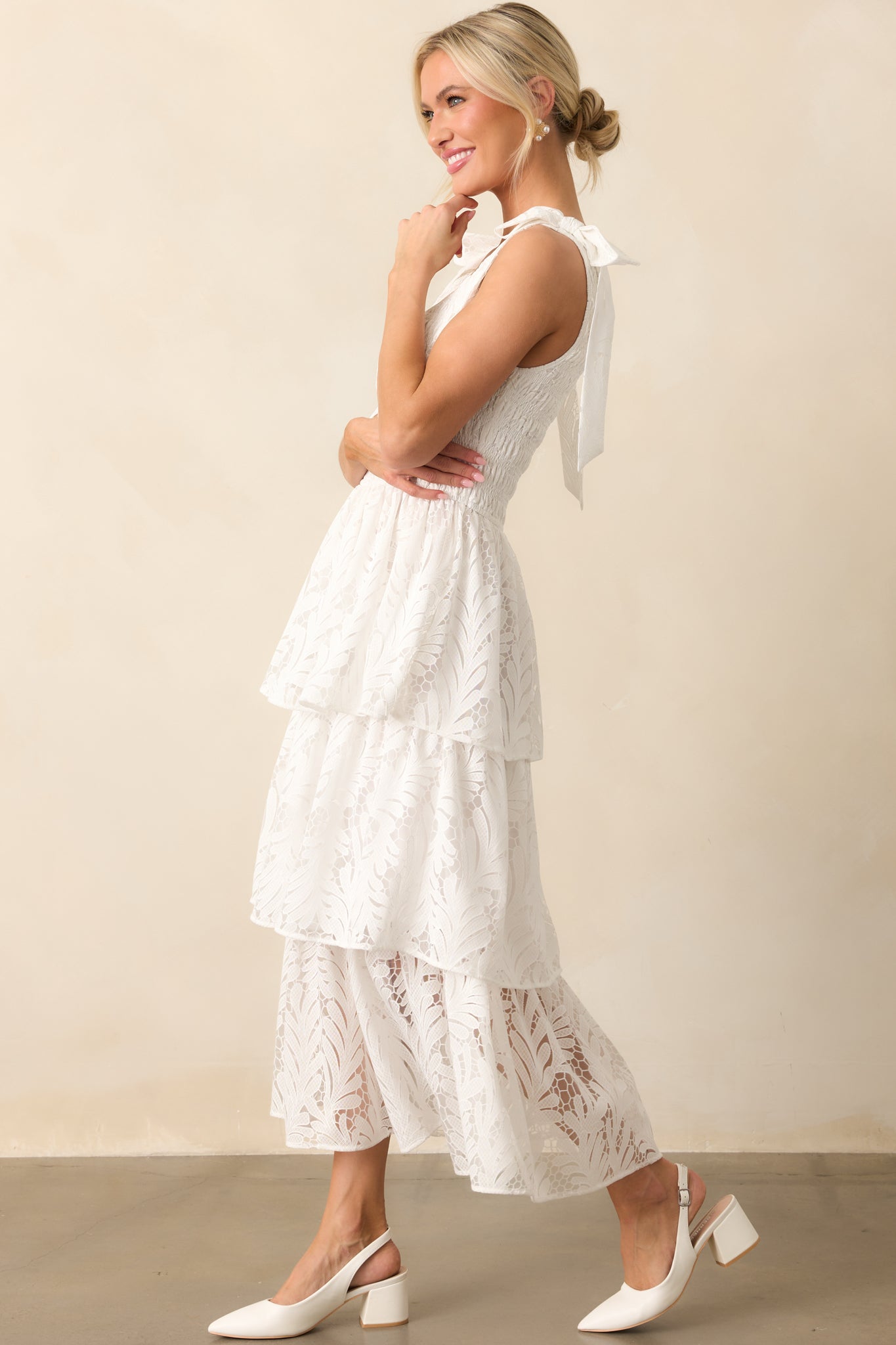 Feminine ivory maxi dress showcasing the scoop neckline, lace bow accents on the shoulders, and the cascading lace tiered design.