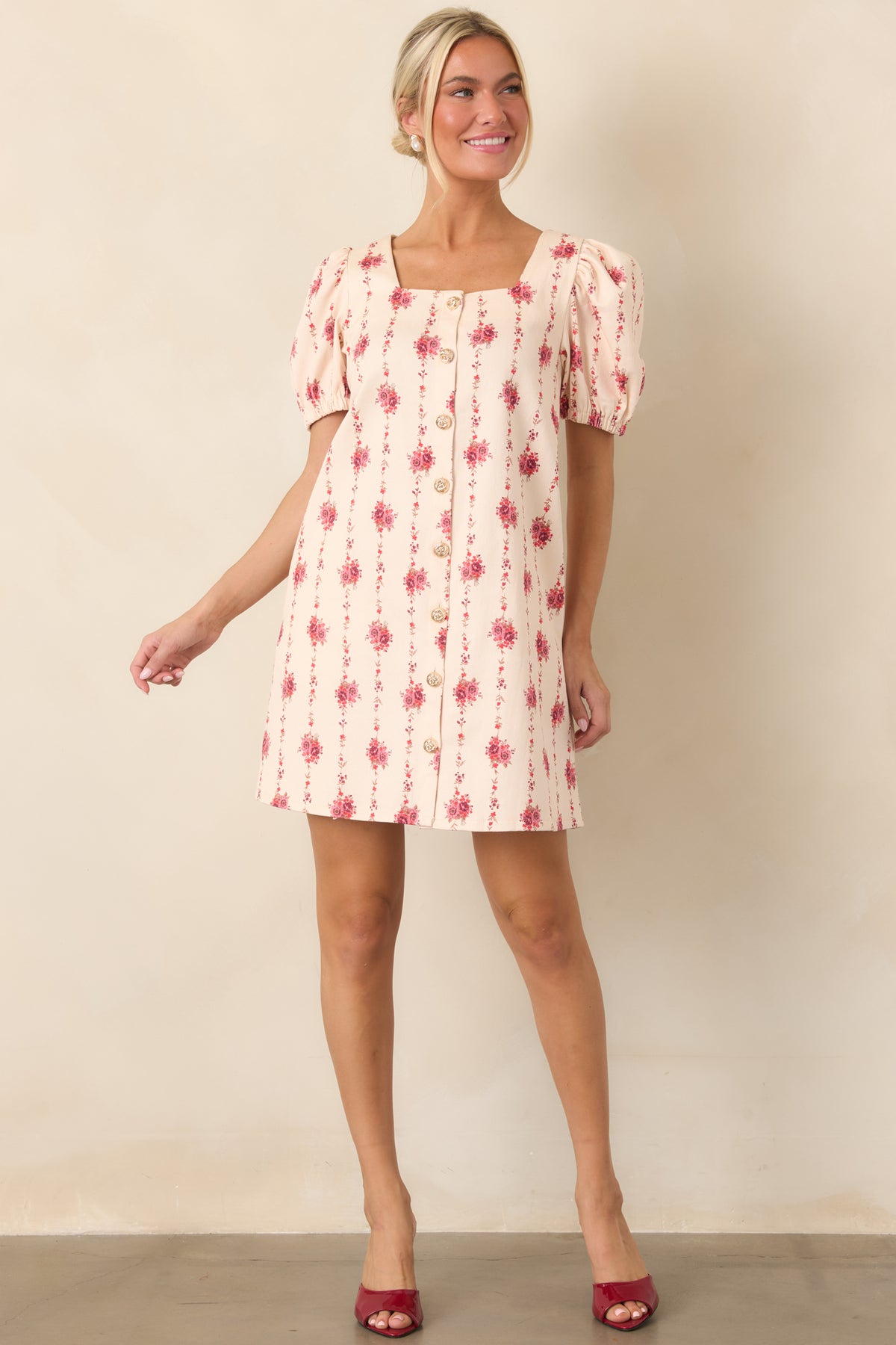 Feminine ivory mini dress designed with vertical floral detailing, decorative gold-tone buttons, and a softly structured silhouette.
