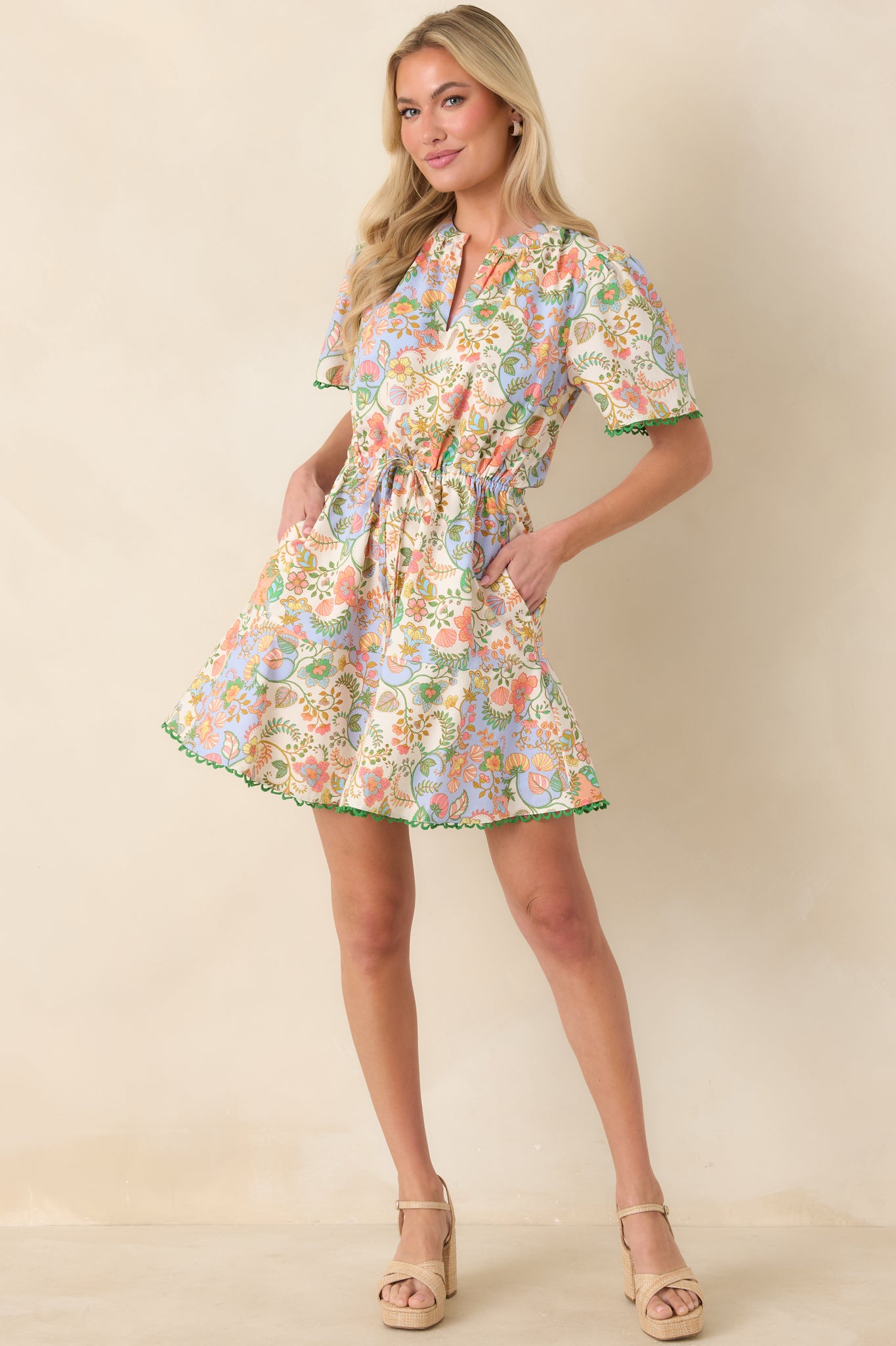 Ivory mini dress featuring a multi floral paisley print, split neckline, short sleeves, and tiered skirt with elasticized waist.