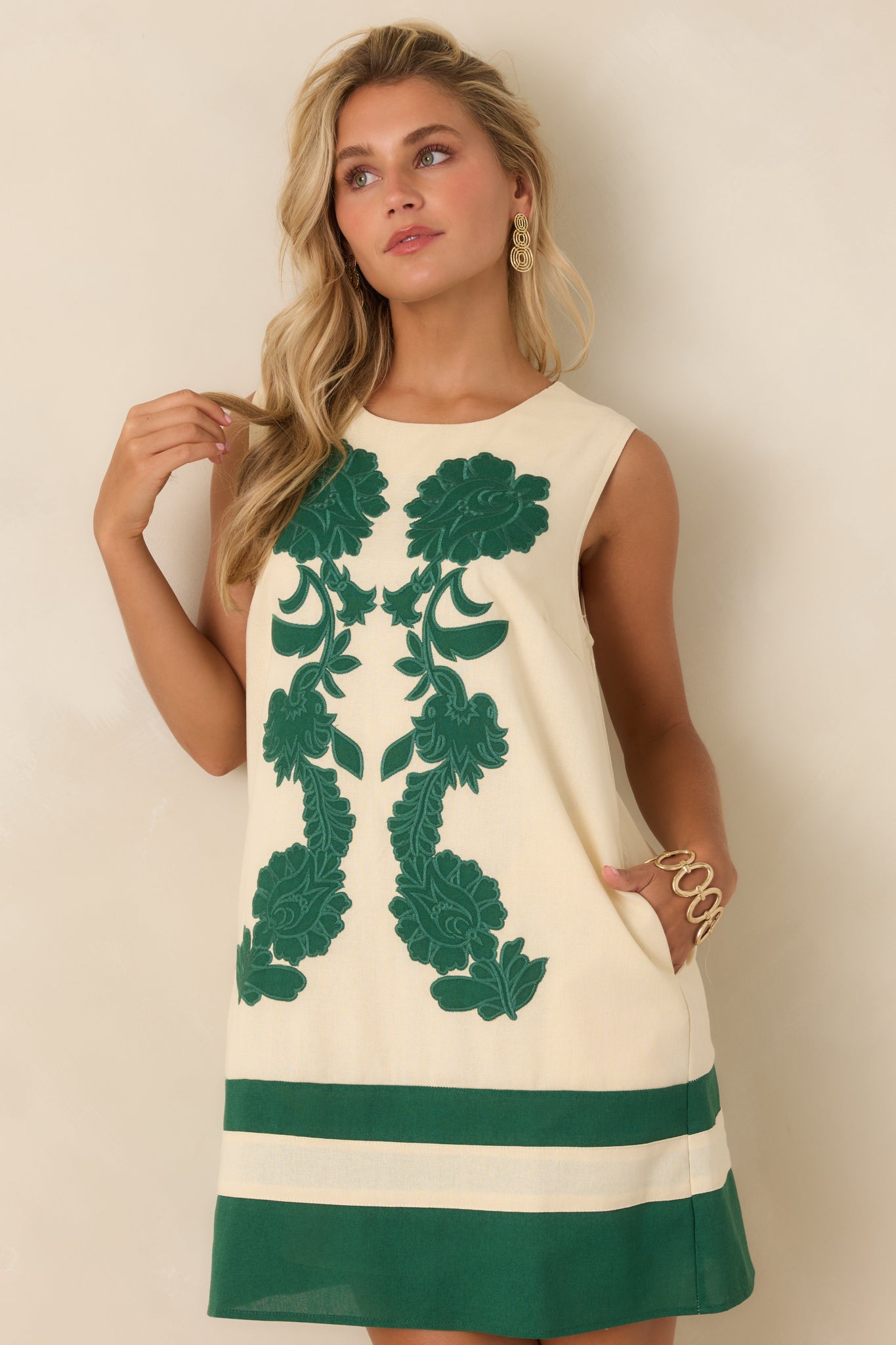 Ivory mini dress highlighting the oversized green floral embroidery, smooth fabric, and detailed appliqué texture.