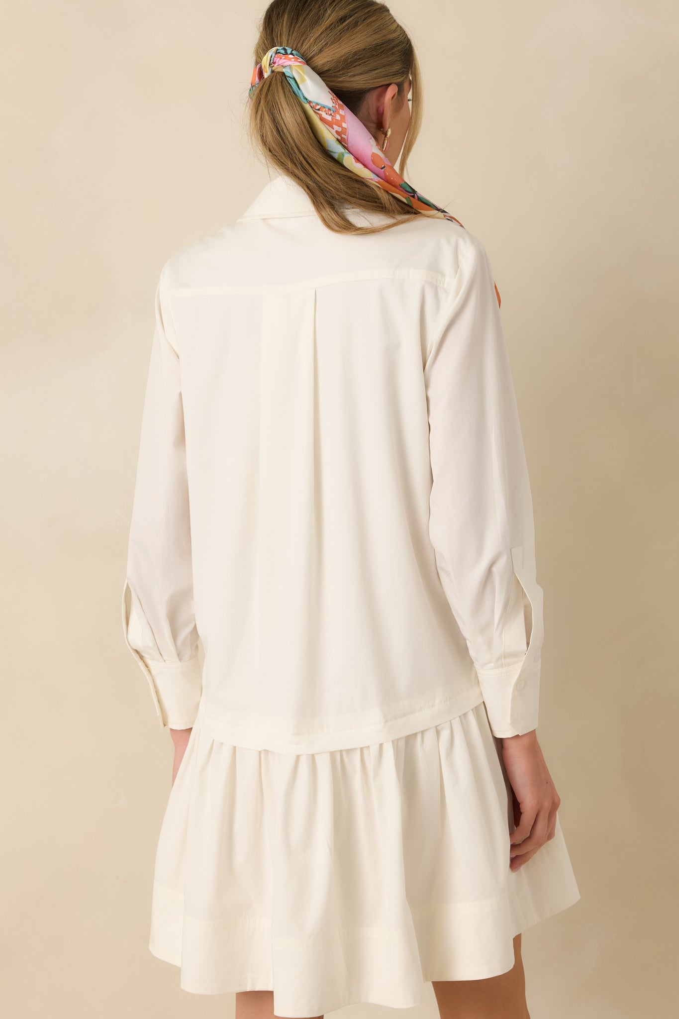Back view of the ivory mini shirt dress highlighting the back yoke with subtle pleating, relaxed fit, and tiered mini hem.