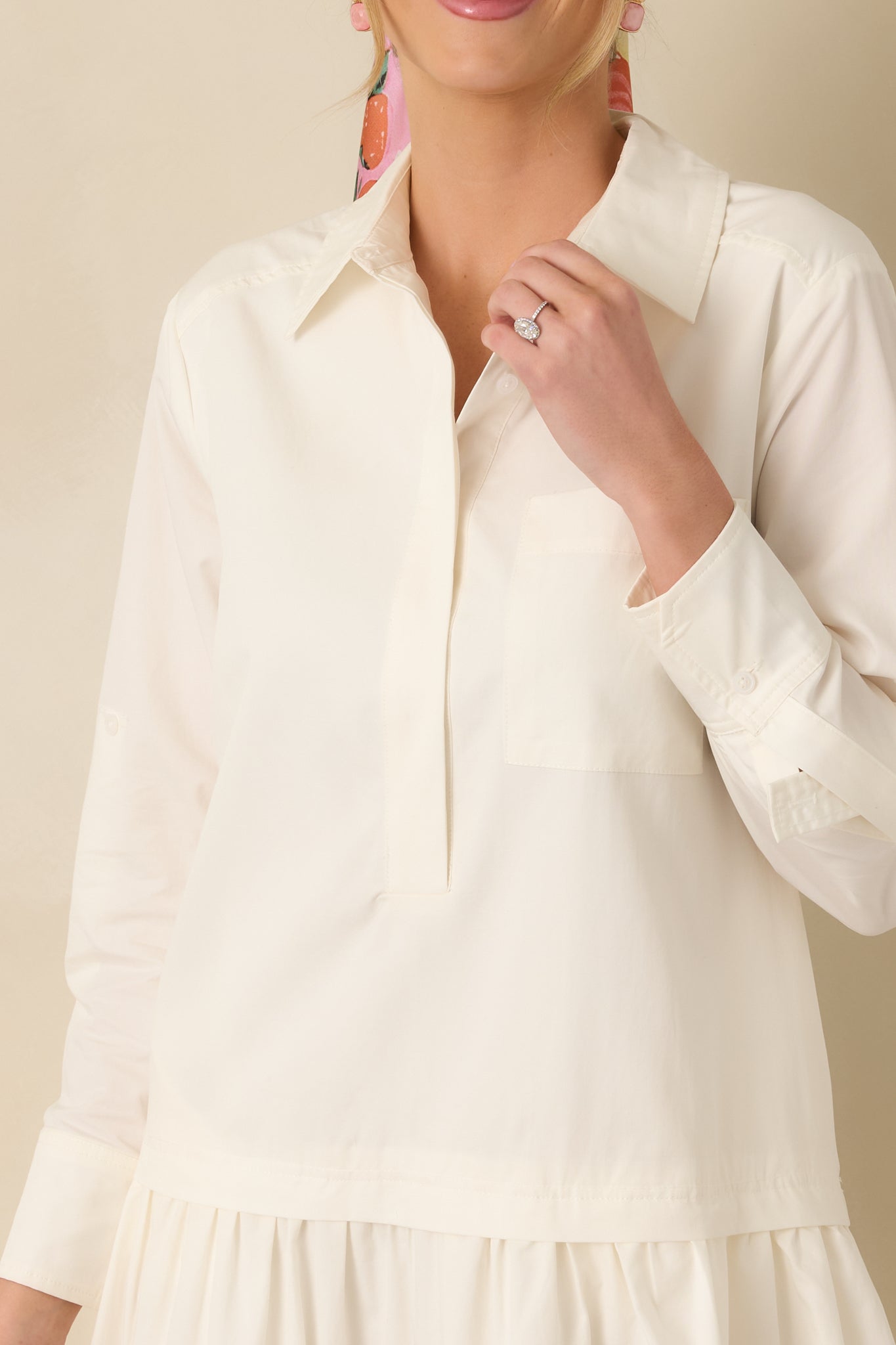 Close-up of the ivory mini shirt dress showing the button placket, fabric texture, and tiered skirt hem detail.