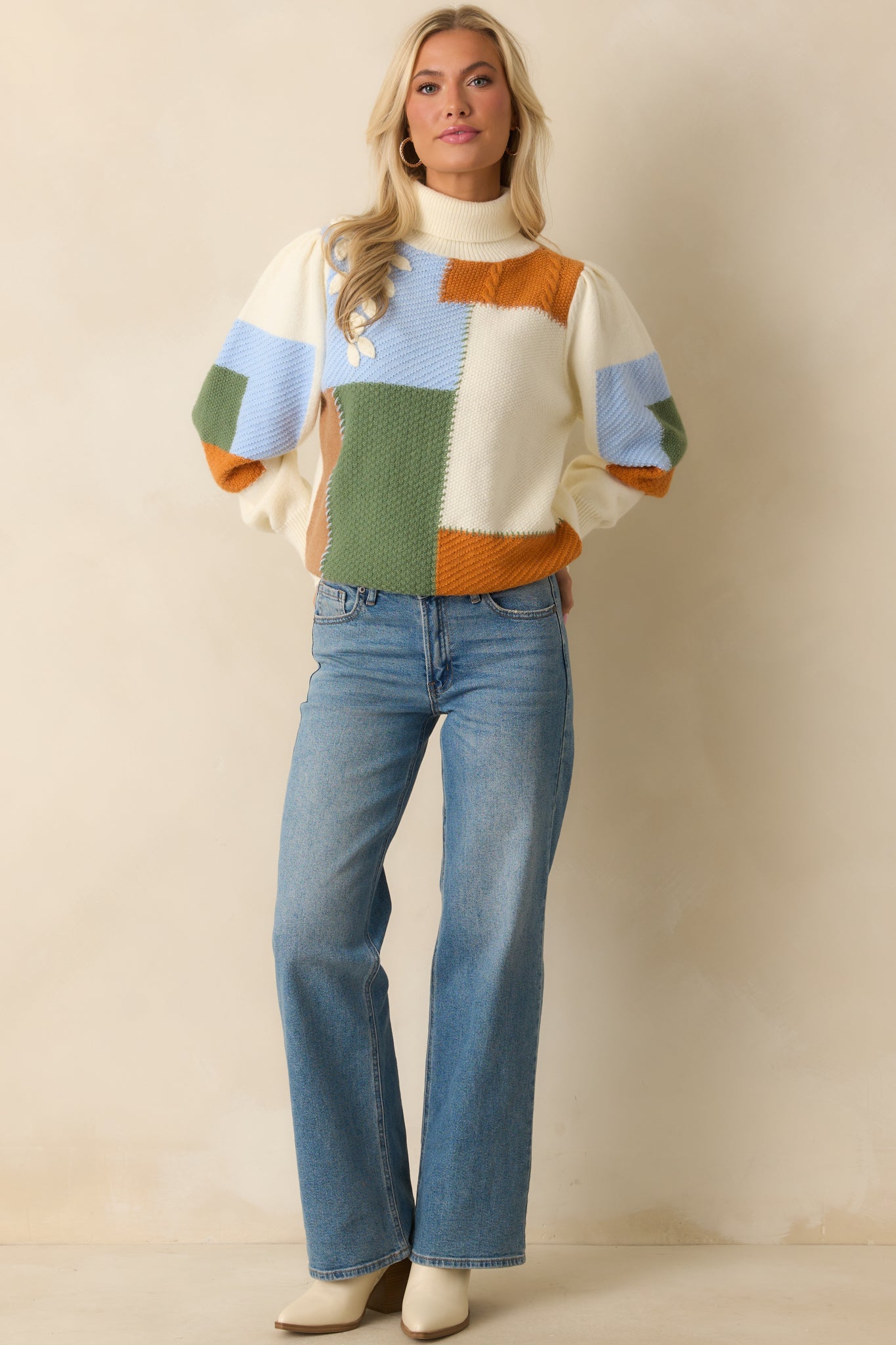Multi-knit patchwork sweater in ivory with ribbed cuffs and hem, accented by colorful green, blue, and rust sections.