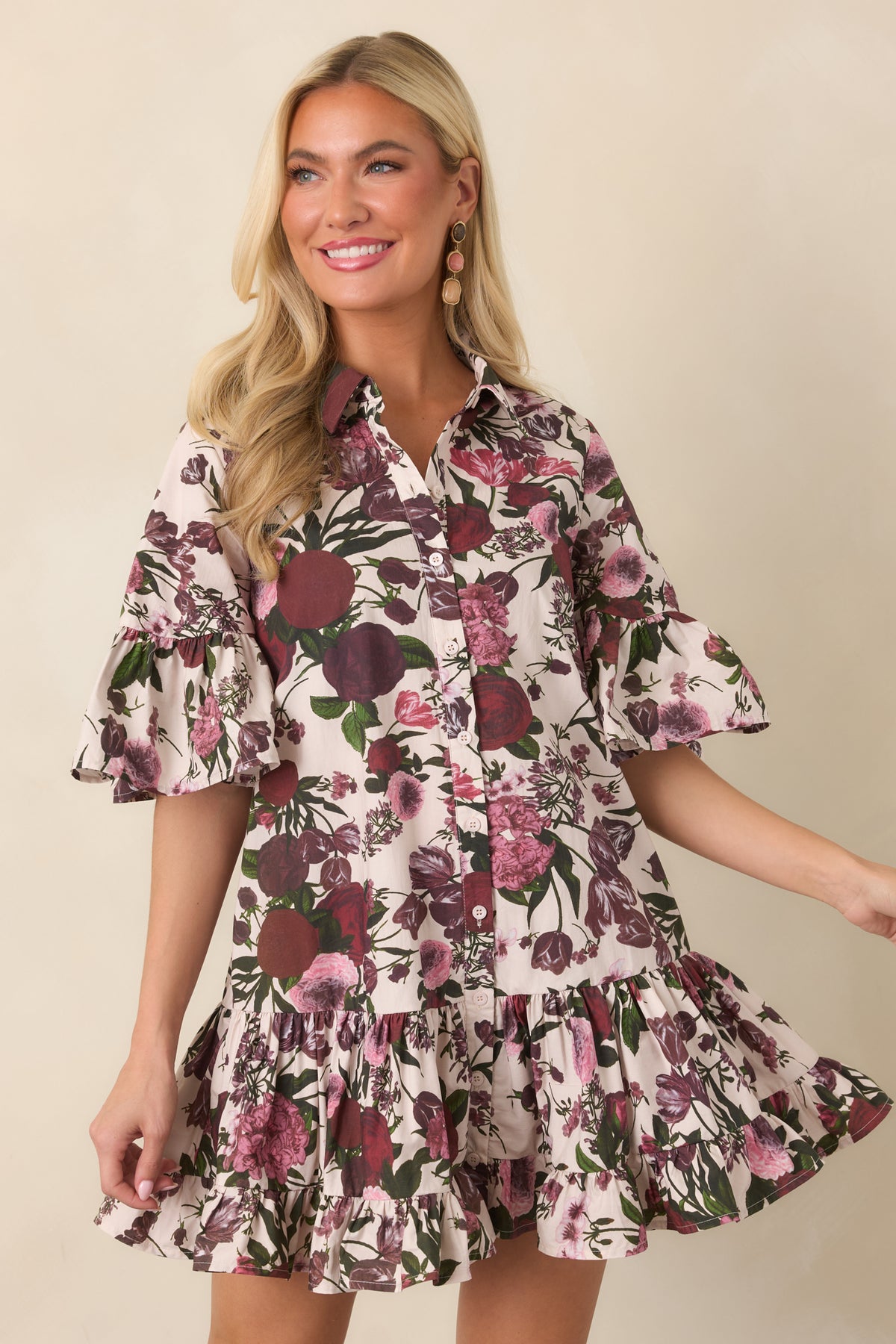 Colorful florals decorate the ivory cotton dress, with delicate ruffle detailing adding texture along the bell sleeves and tiered skirt.