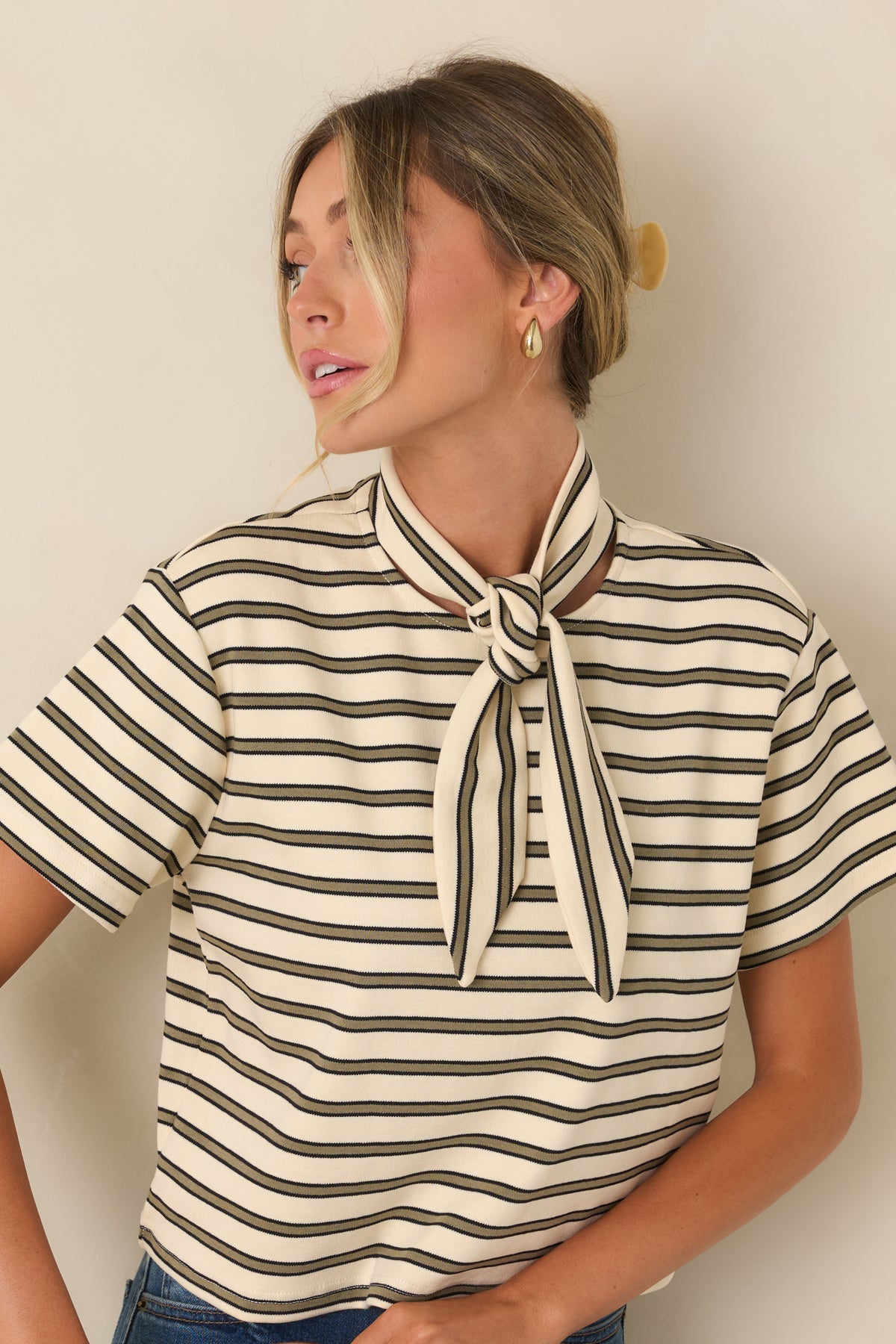 Close view of the tee highlighting the slim olive horizontal stripes, ivory fabric, and soft cotton-blend texture.