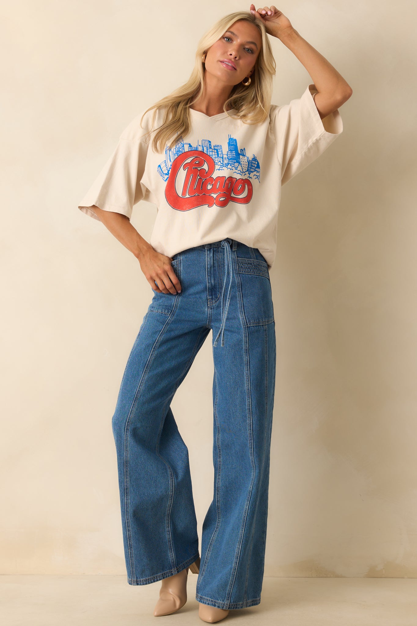 Ivory oversized T-shirt with bold red “Chicago” script over blue skyline, shown with v-stitch crew neckline and wide short sleeves.

