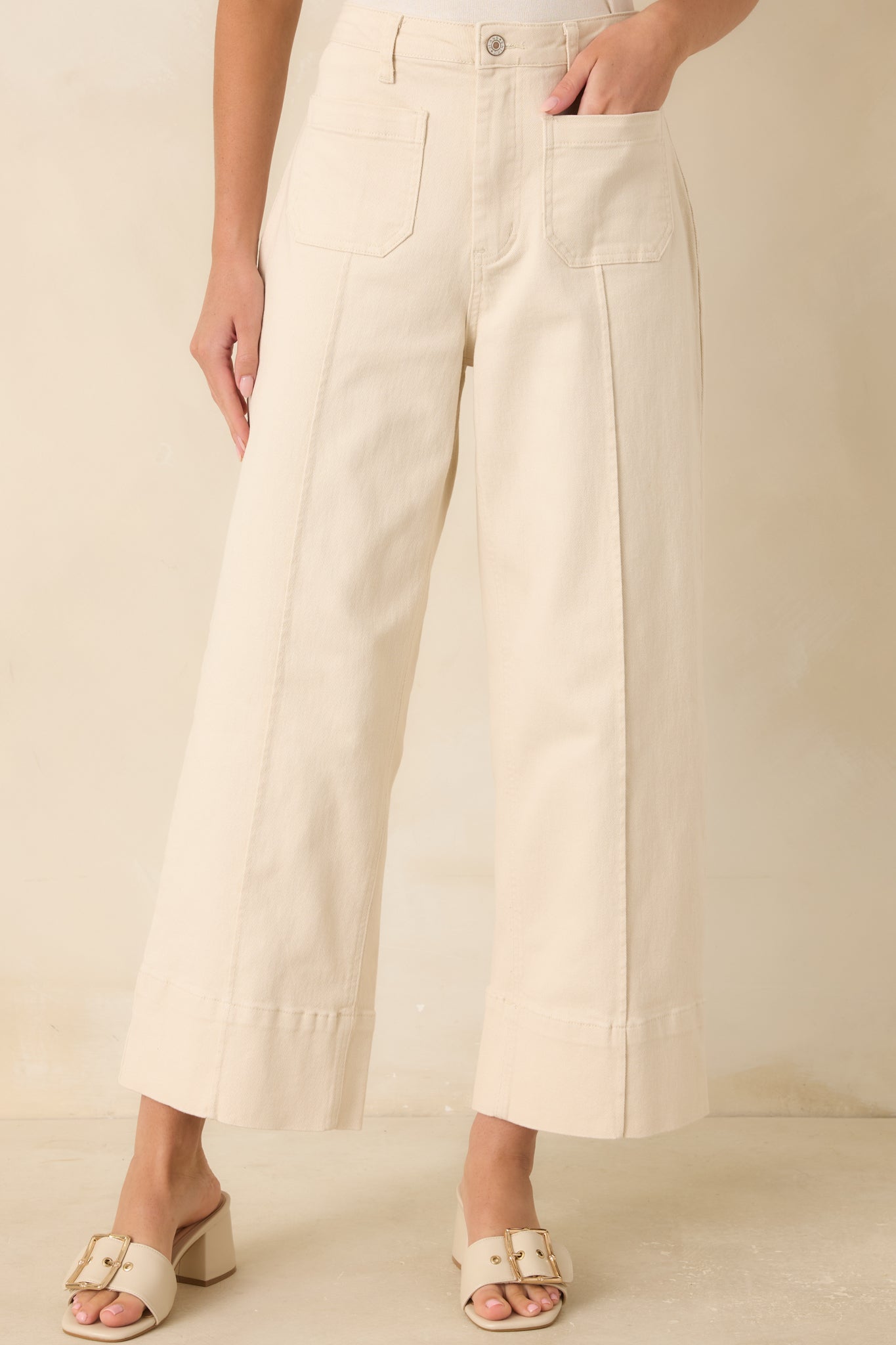 Detailed view of the pressed center seams and smooth ivory fabric highlighting the structured pant design.