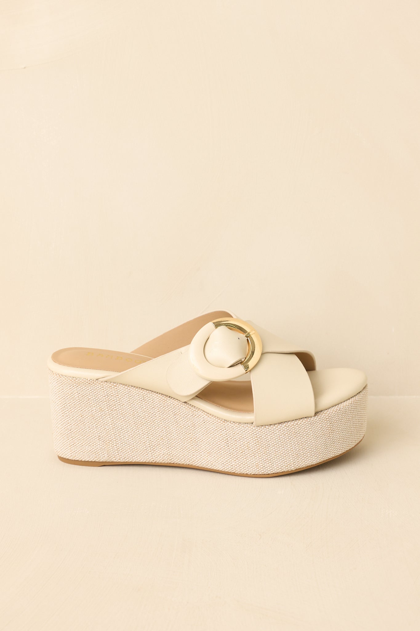 Ivory platform wedge sandals displayed on a beige background, side angle emphasizing the contrast between the smooth upper and textured wedge.