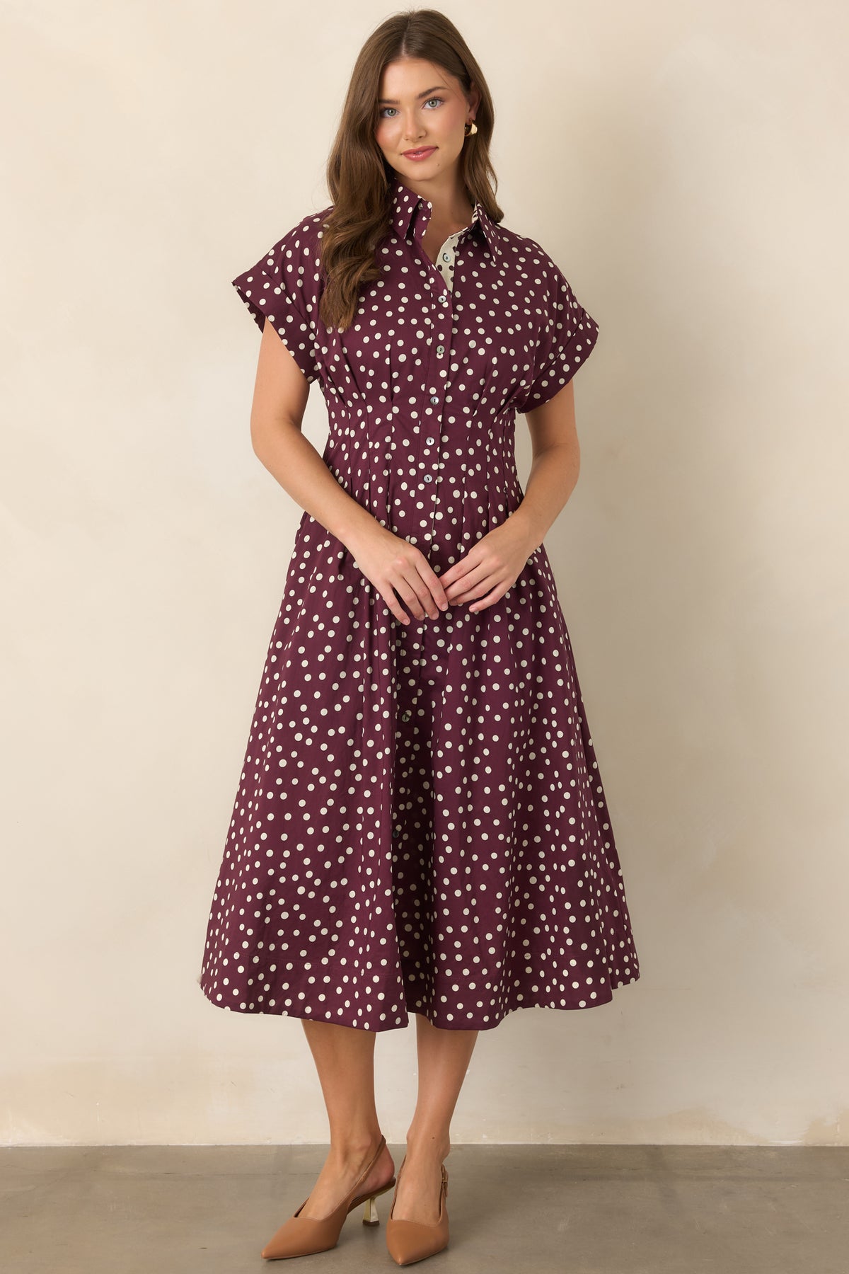 Ivory and plum polka dot cotton midi dress with a structured collar, short sleeves, button-front closure, tailored waist seams, and a flowing flared skirt.