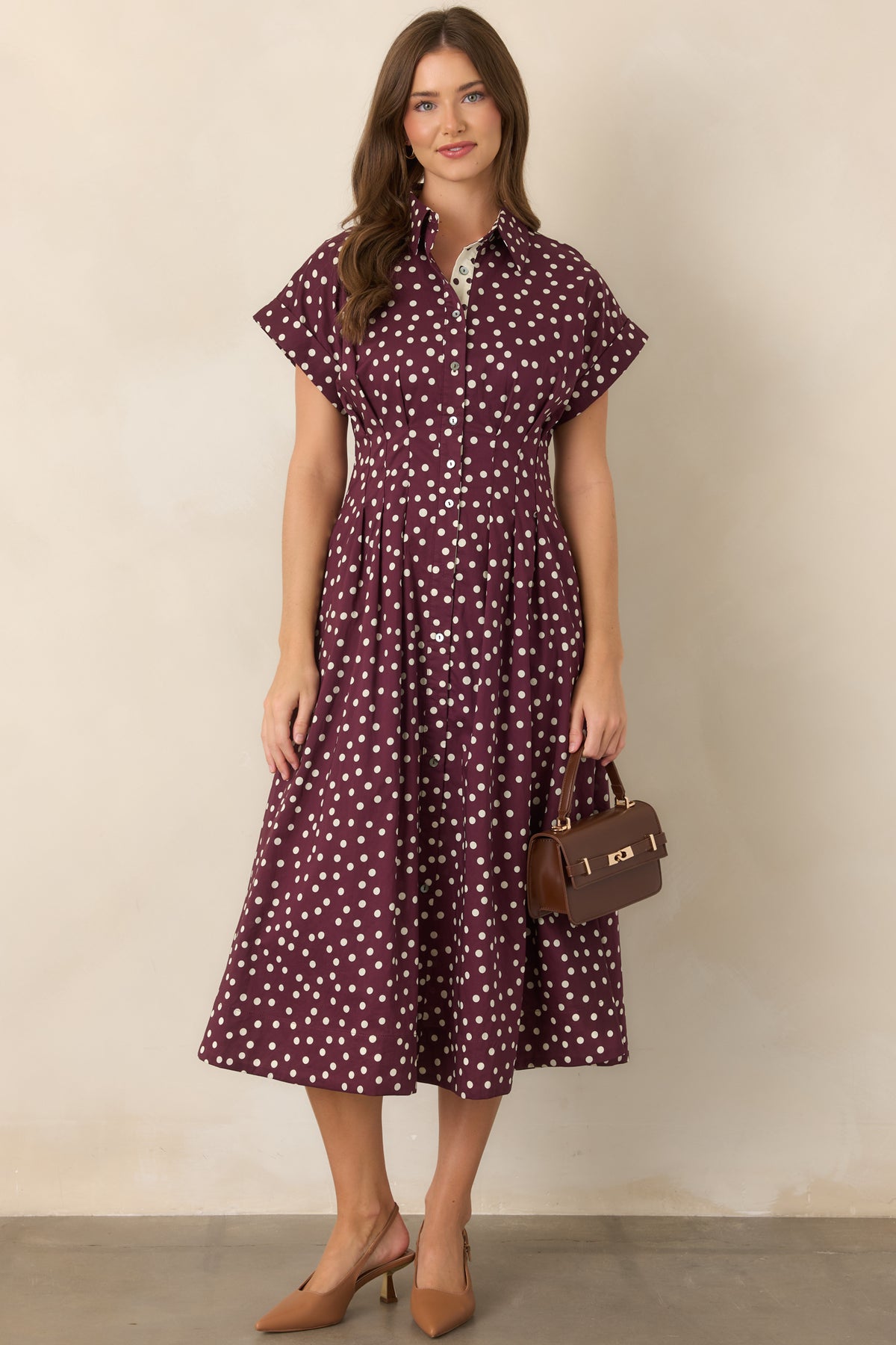 Ivory and plum printed midi dress with a collared neckline, short sleeves, button-front design, fitted waist, and flowing skirt with convenient side pockets.