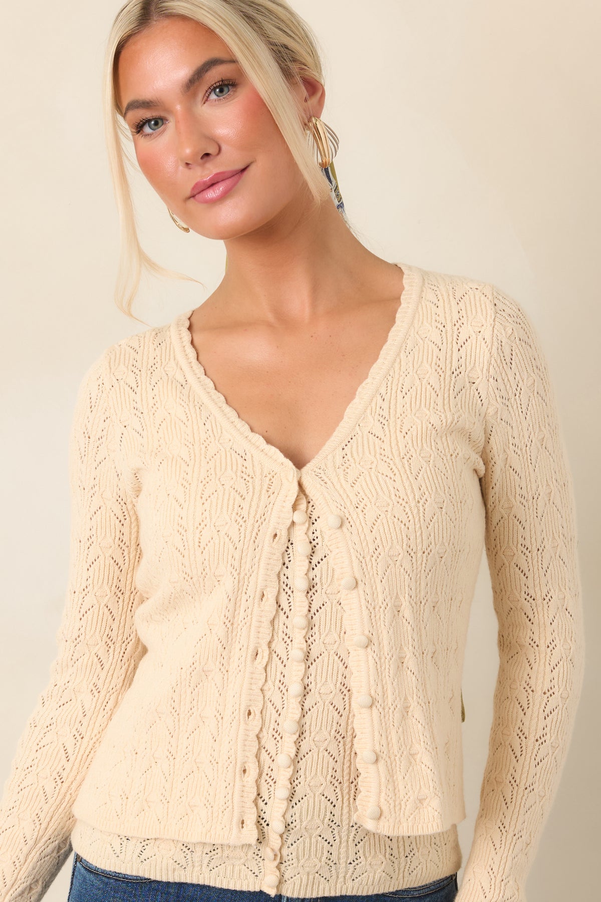 Detailed view of the cropped cardigan showcasing its textured pointelle knit and polished row of functional front buttons.