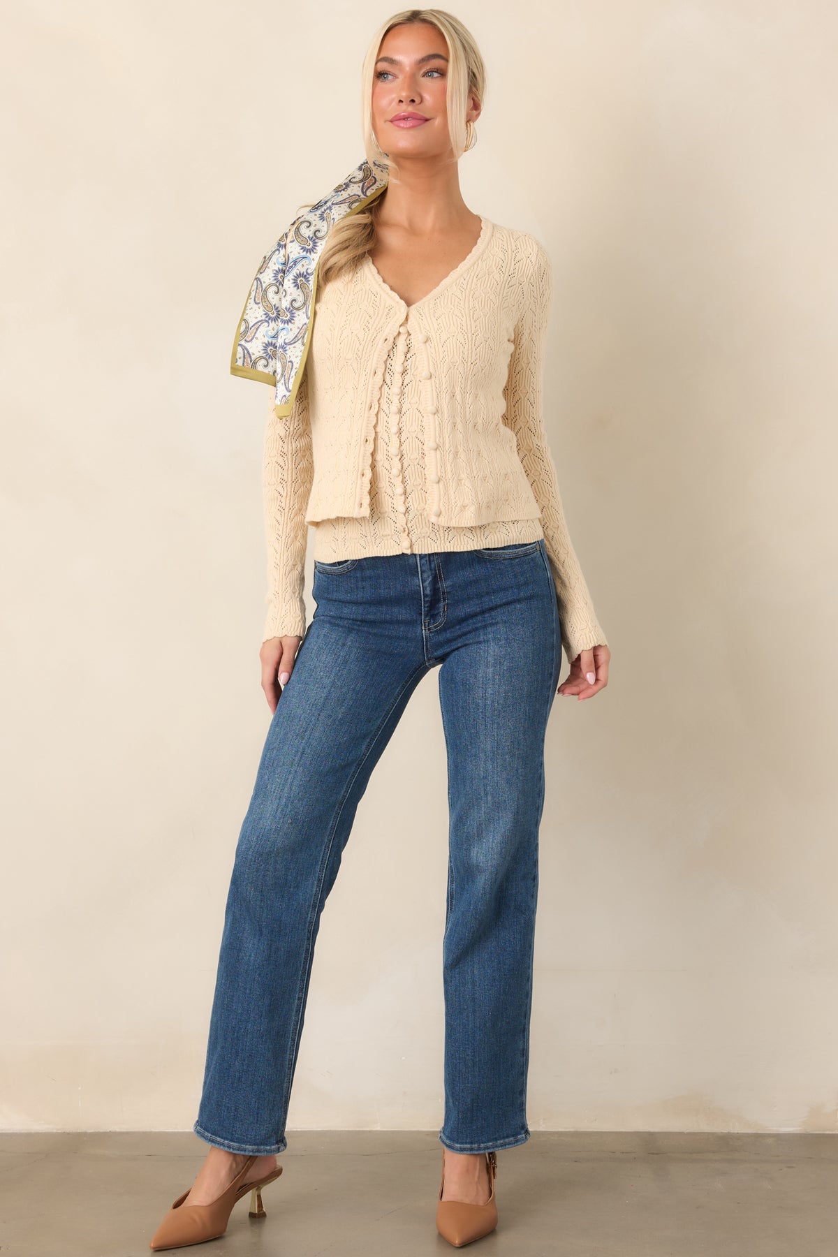 Cropped ivory cardigan with delicate pointelle texture, scalloped V-neckline, full-length sleeves, and neatly spaced front buttons.